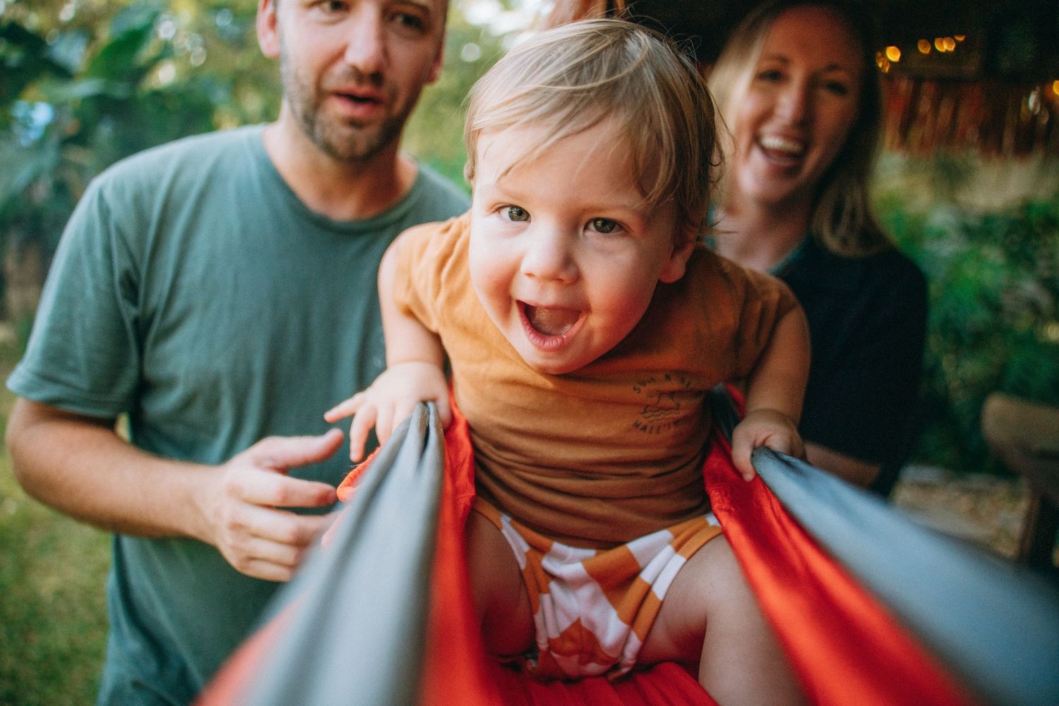 Heartwarming family interactions captured beneath a rustic thatched roof with string lights.