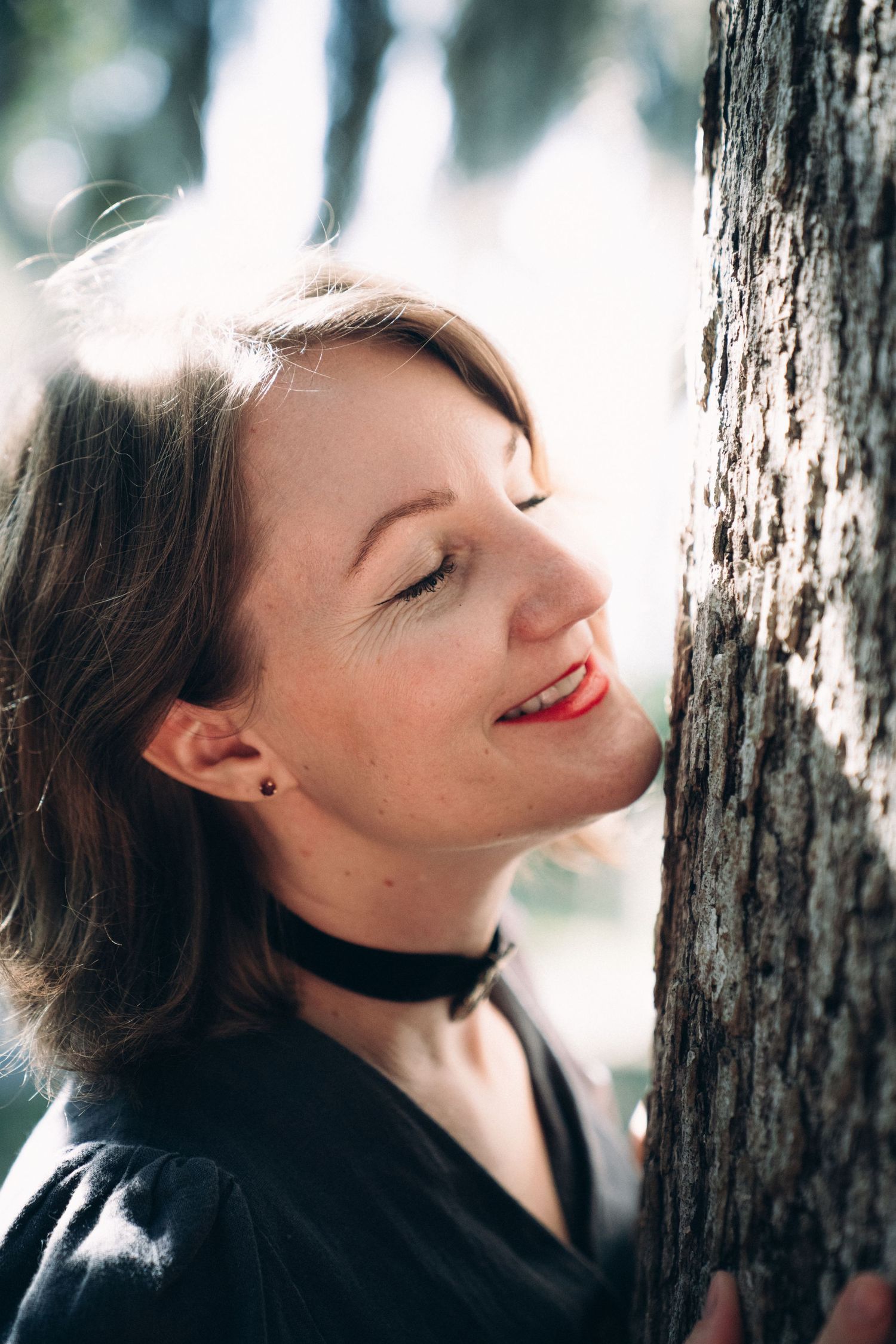 A dreamy winter portrait sequence showing someone leaning against a tree trunk with closed eyes.