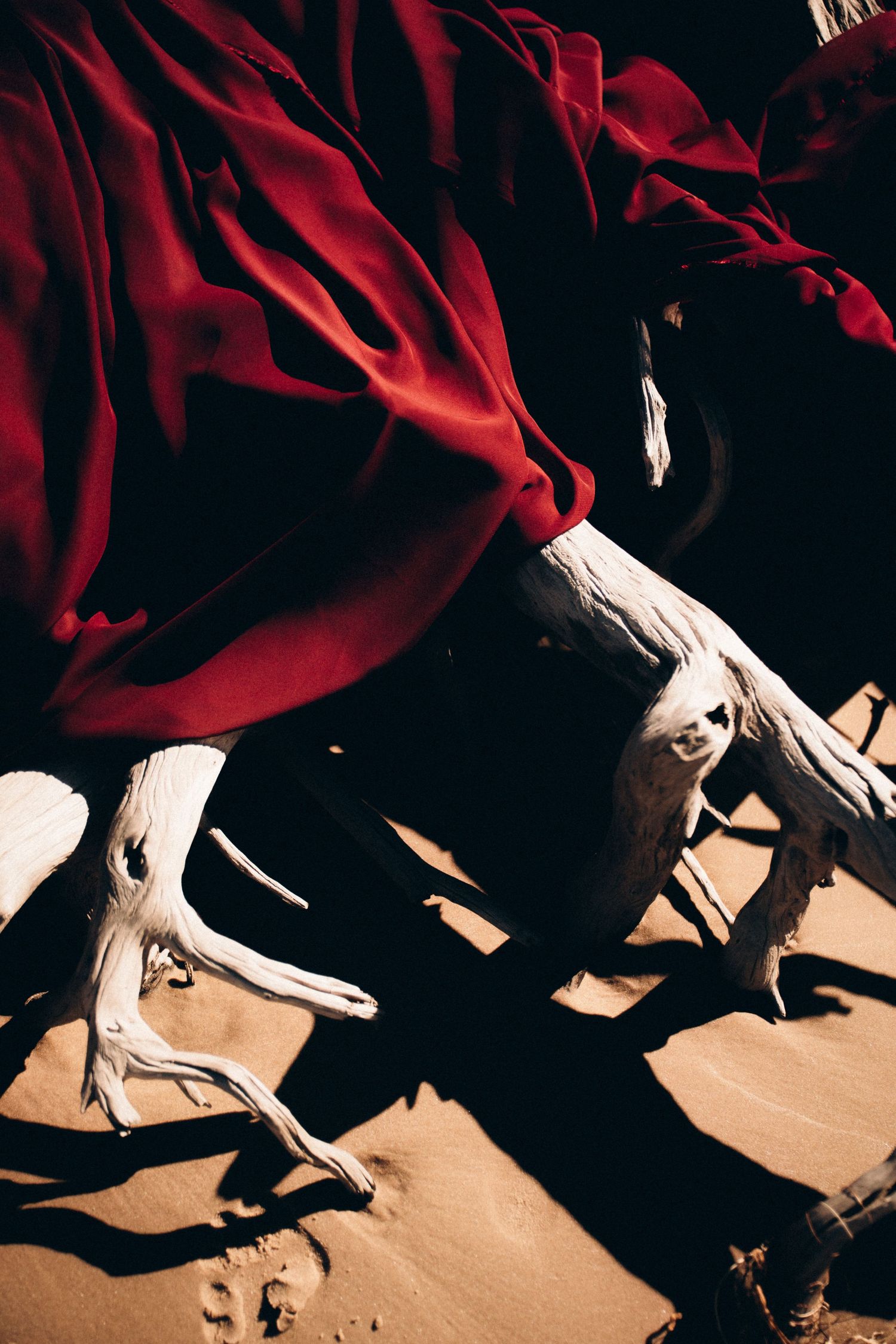 Dramatic shadows cast by dancers in red costumes performing on a beige stage.