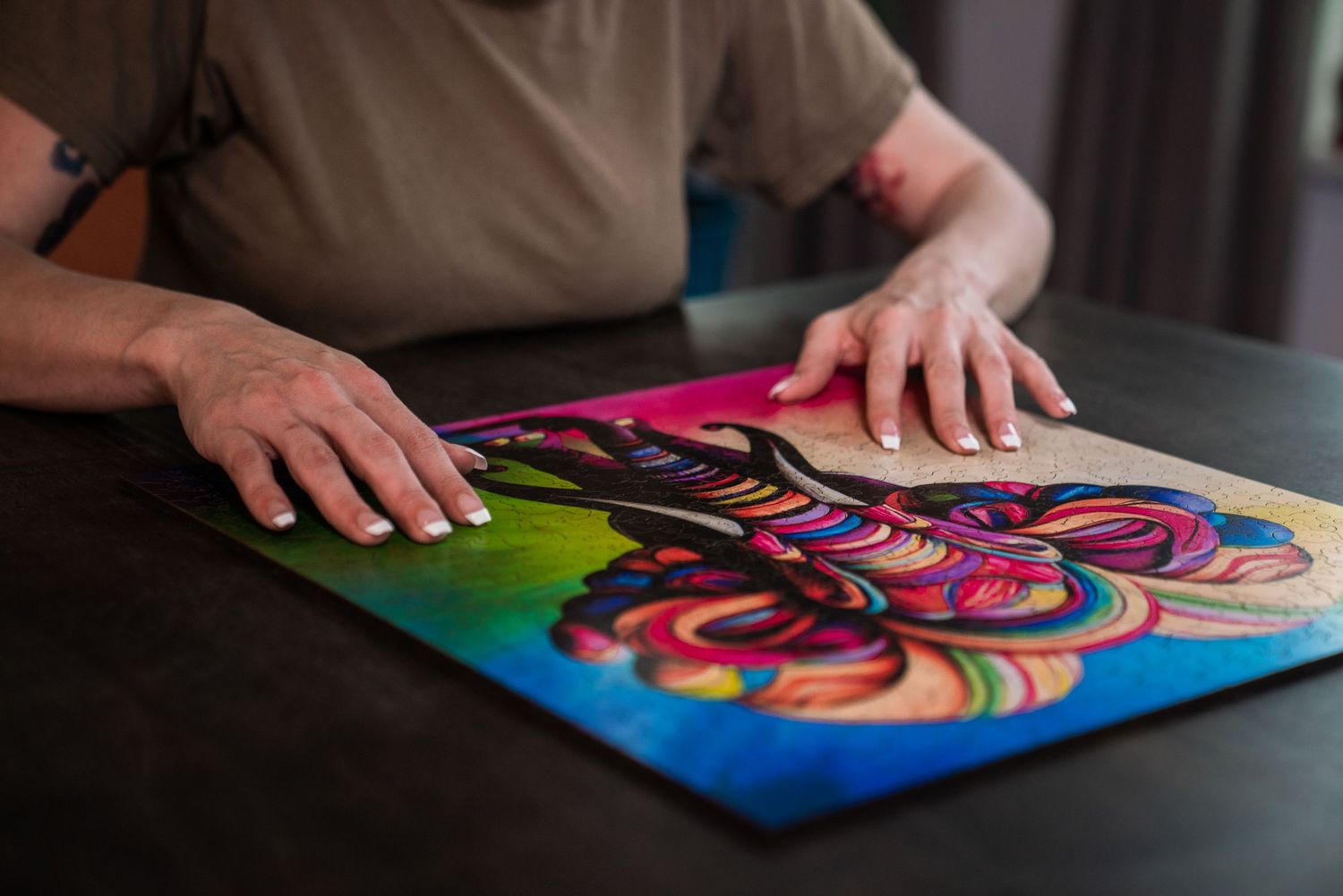 Person placing hands on vibrant colorful abstract artwork with swirling rainbow patterns on a dark table.