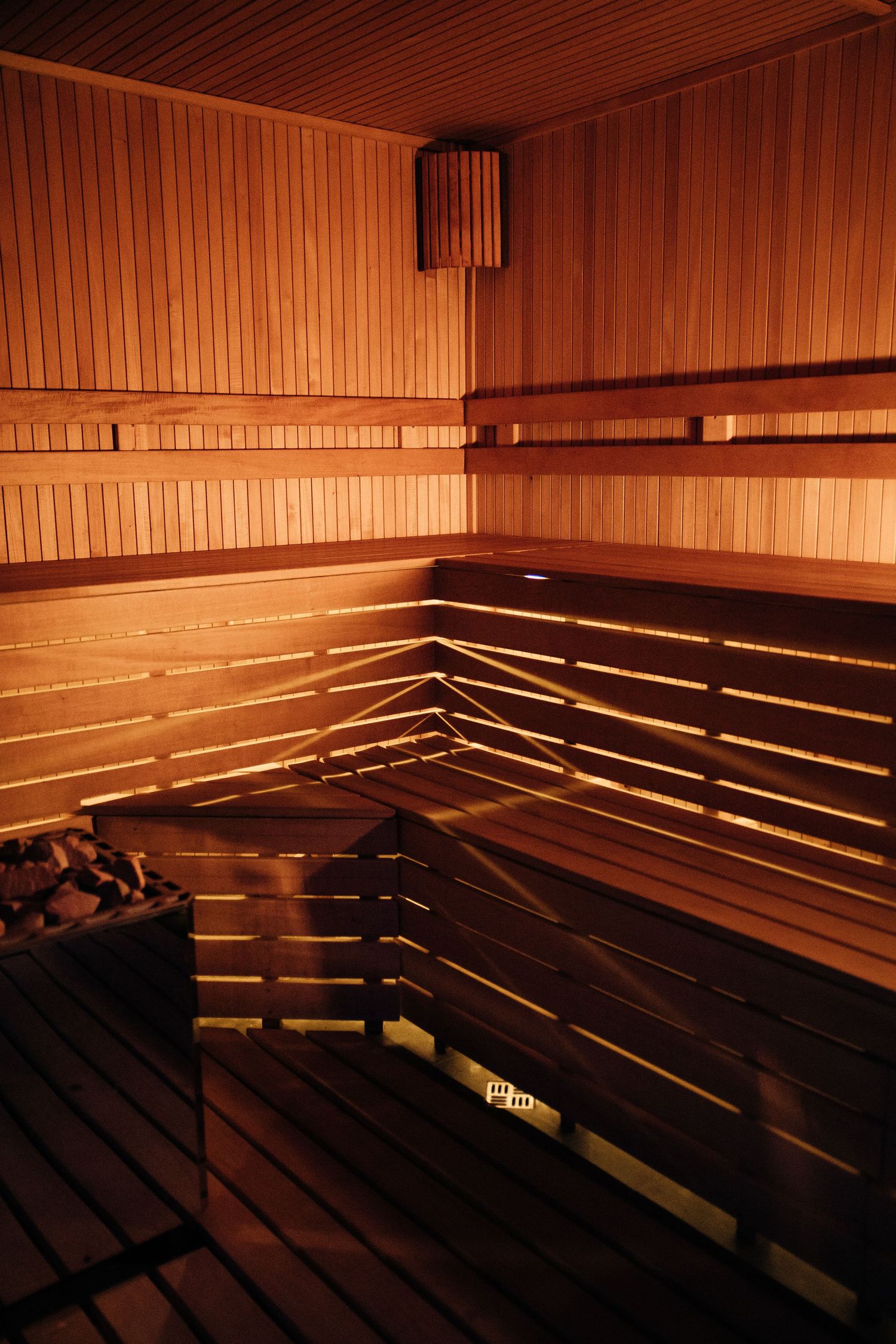 Warm wooden Finnish sauna interior with tiered benches and traditional stone heater.