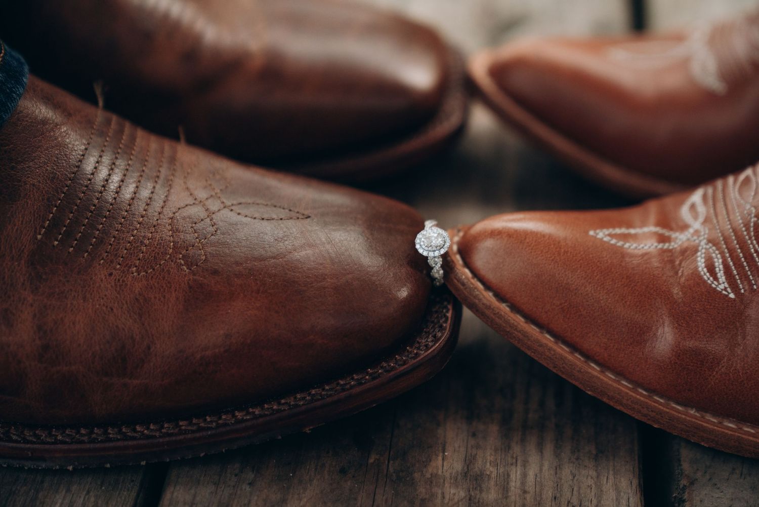 Close-up detail shot of brown leather cowboy boots side by side on a textured surface.