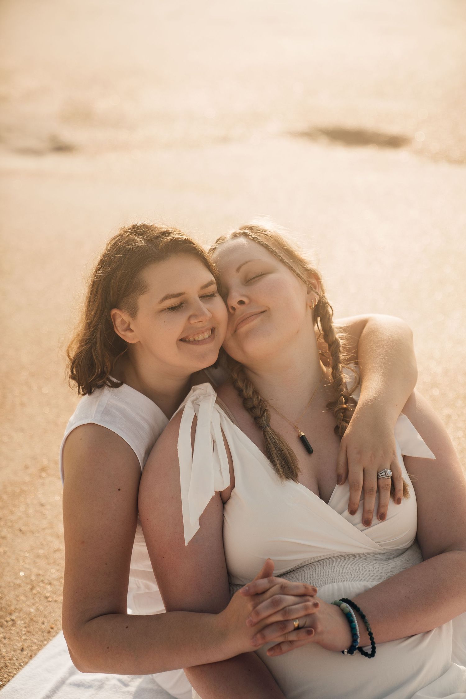A tender beach moment captured between two people during sunset.