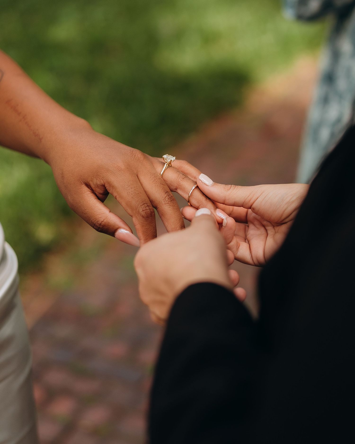 Close-up of hands exchanging rings during an outdoor wedding ceremony.