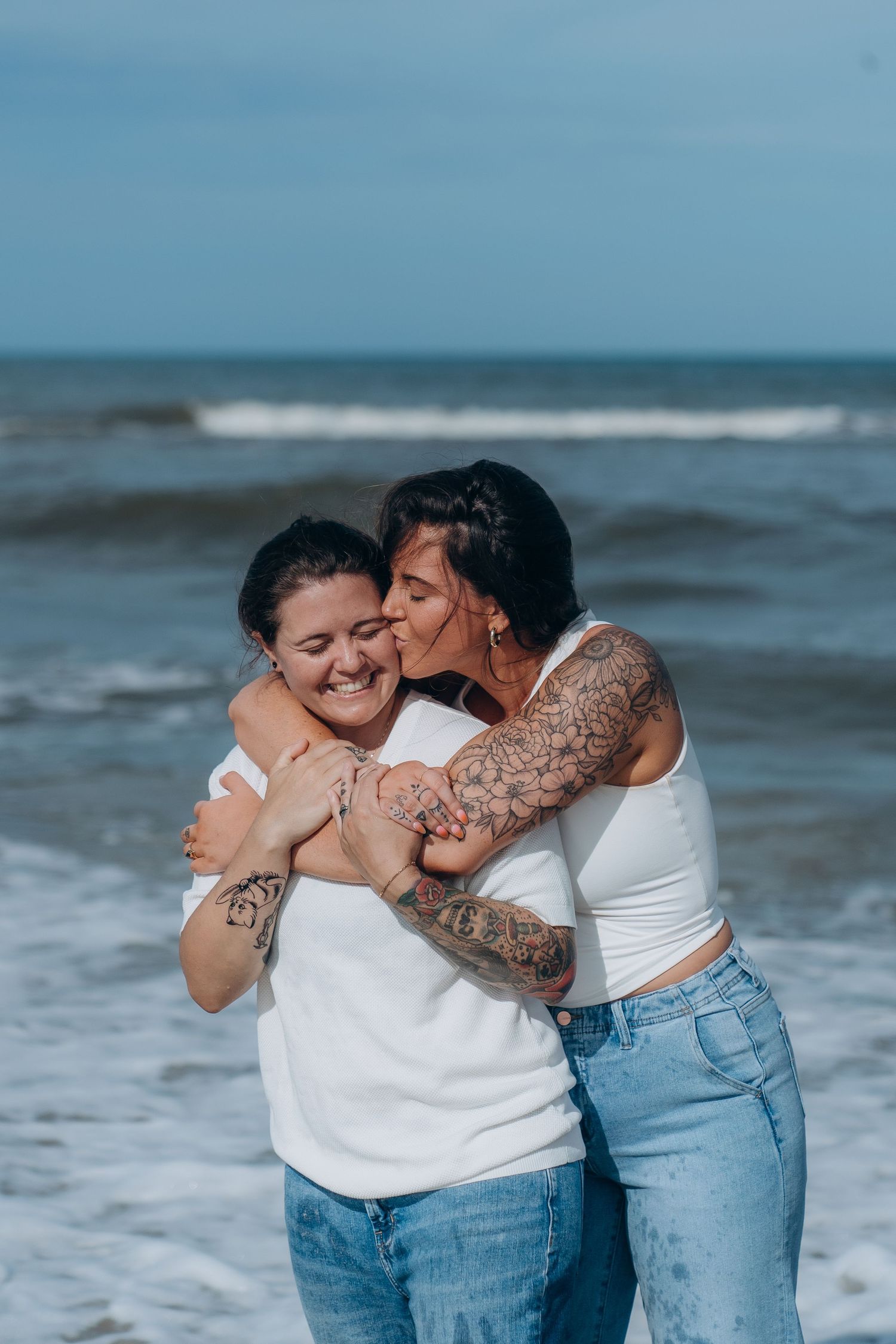 A couple sharing affectionate embraces by the ocean waves.