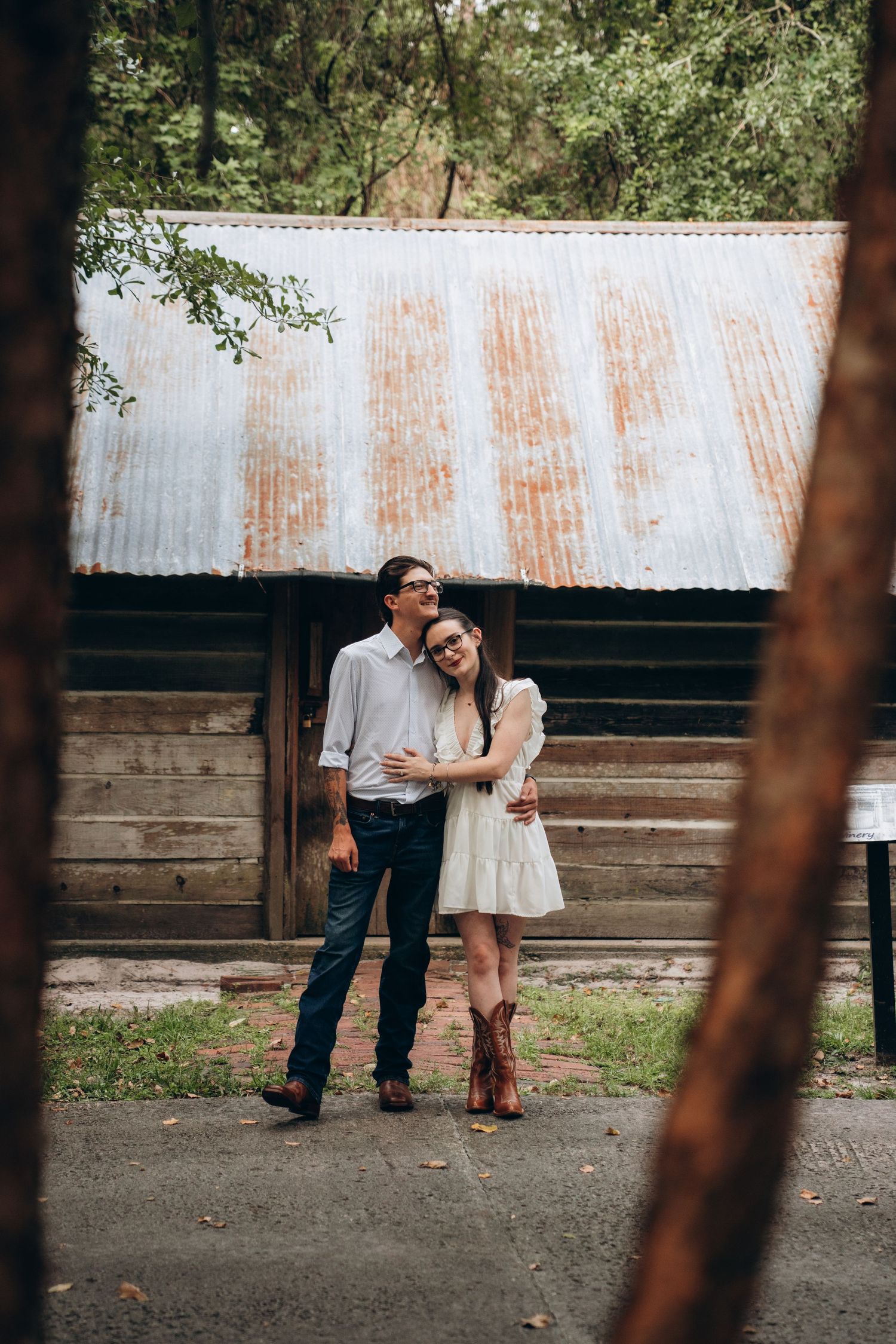 Rustic outdoor wedding scene with couples standing against wooden fence and corrugated metal backdrop.