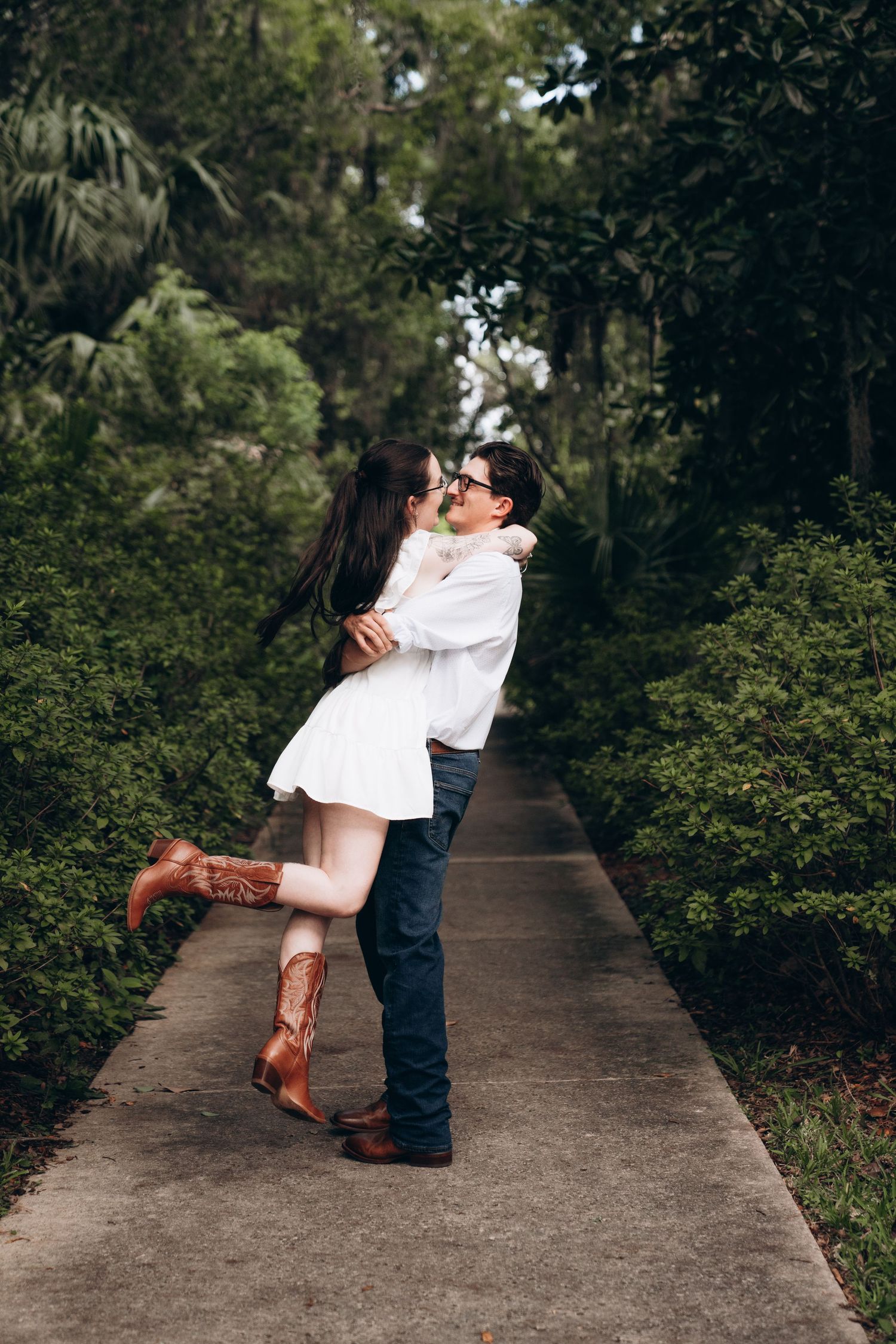 Romantic dance sequence on concrete pathway surrounded by lush greenery.