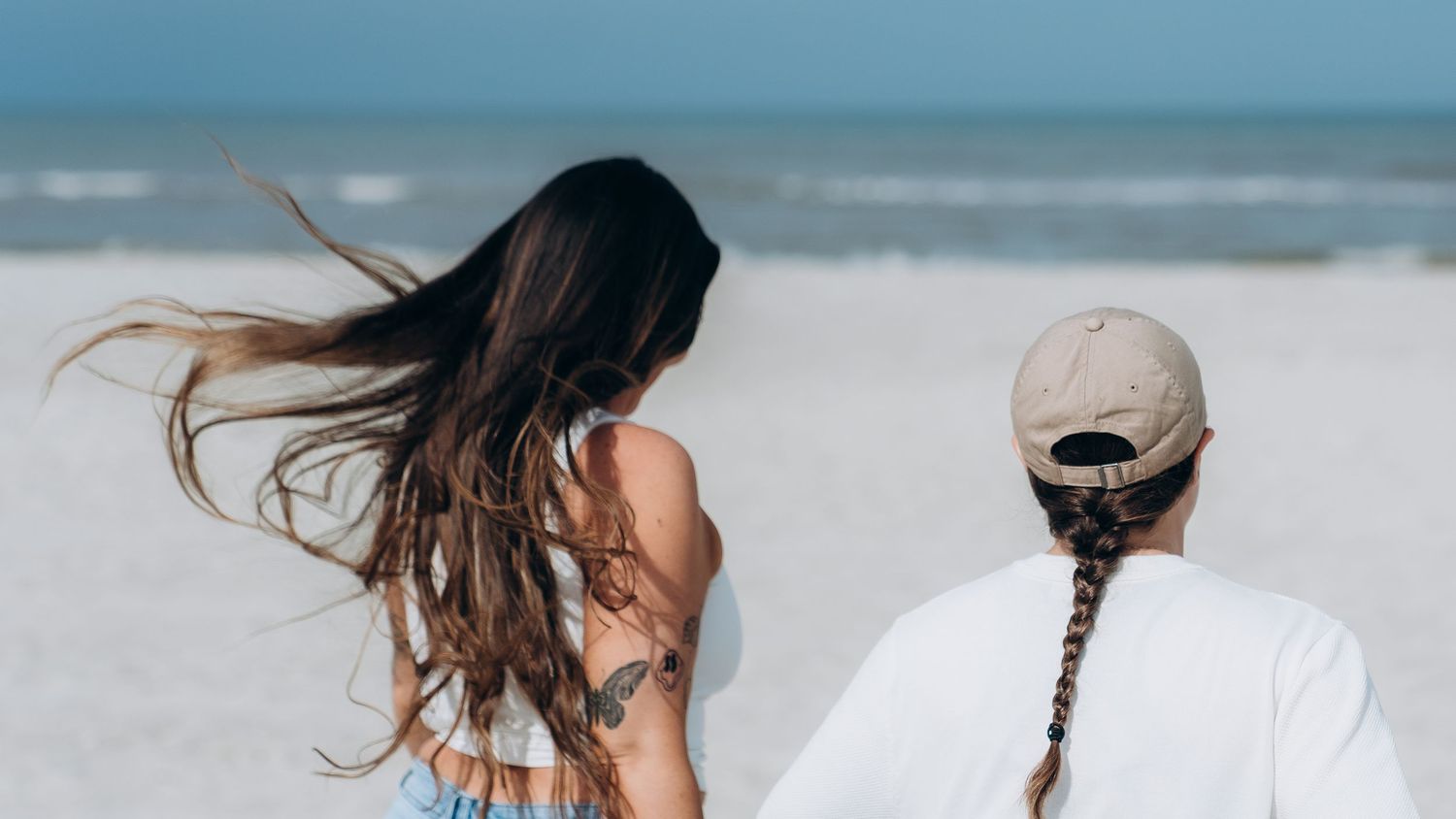 Couple enjoying a romantic moment on beach with wind blowing through their hair.