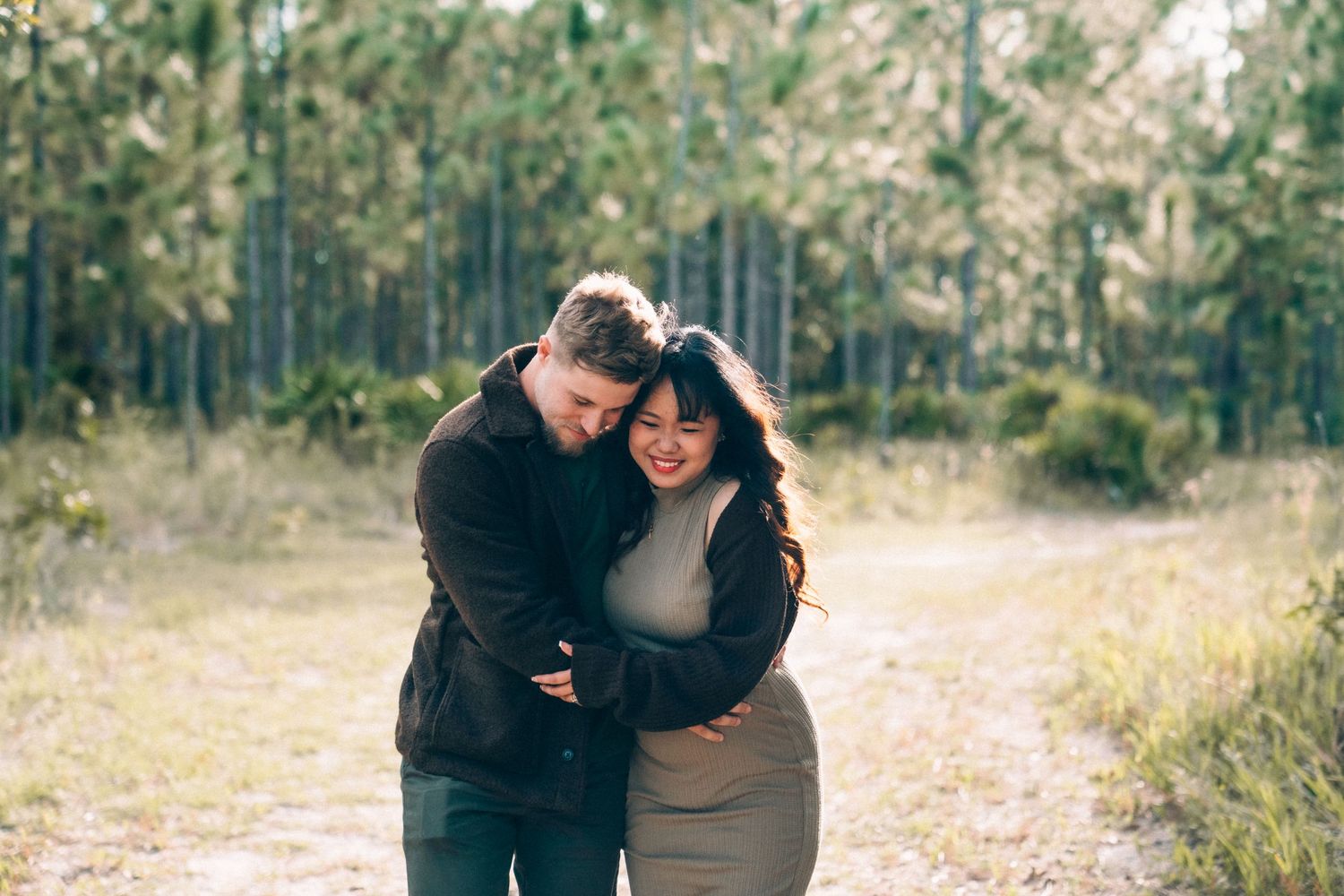 A couple shares an intimate moment while walking together on a wooded path during autumn.