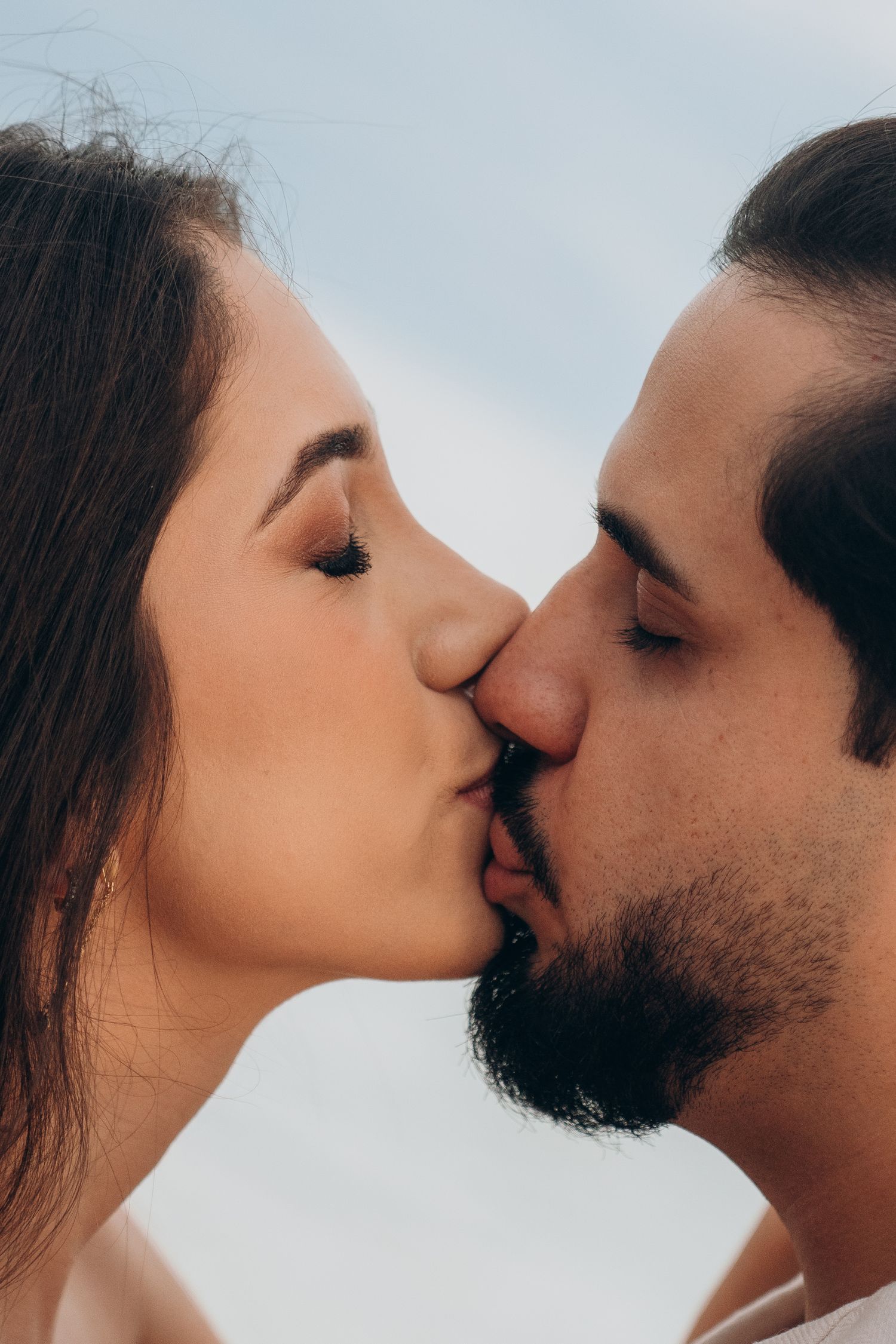 Close-up sequence of a romantic kiss against a bright sky background.