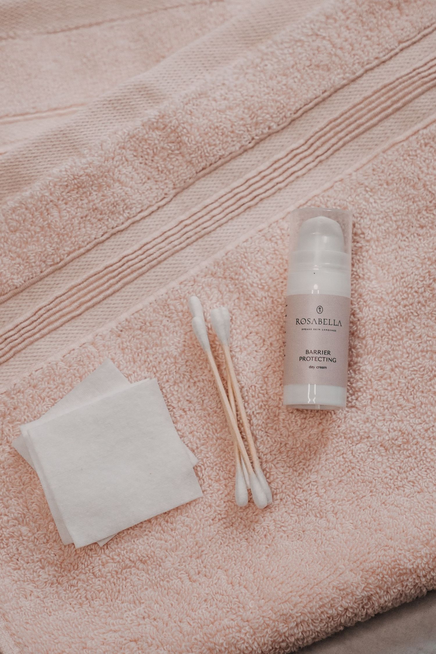 Rosabella Barrier Protecting Gel on a pink towel with cotton pads and swabs for a skincare routine.