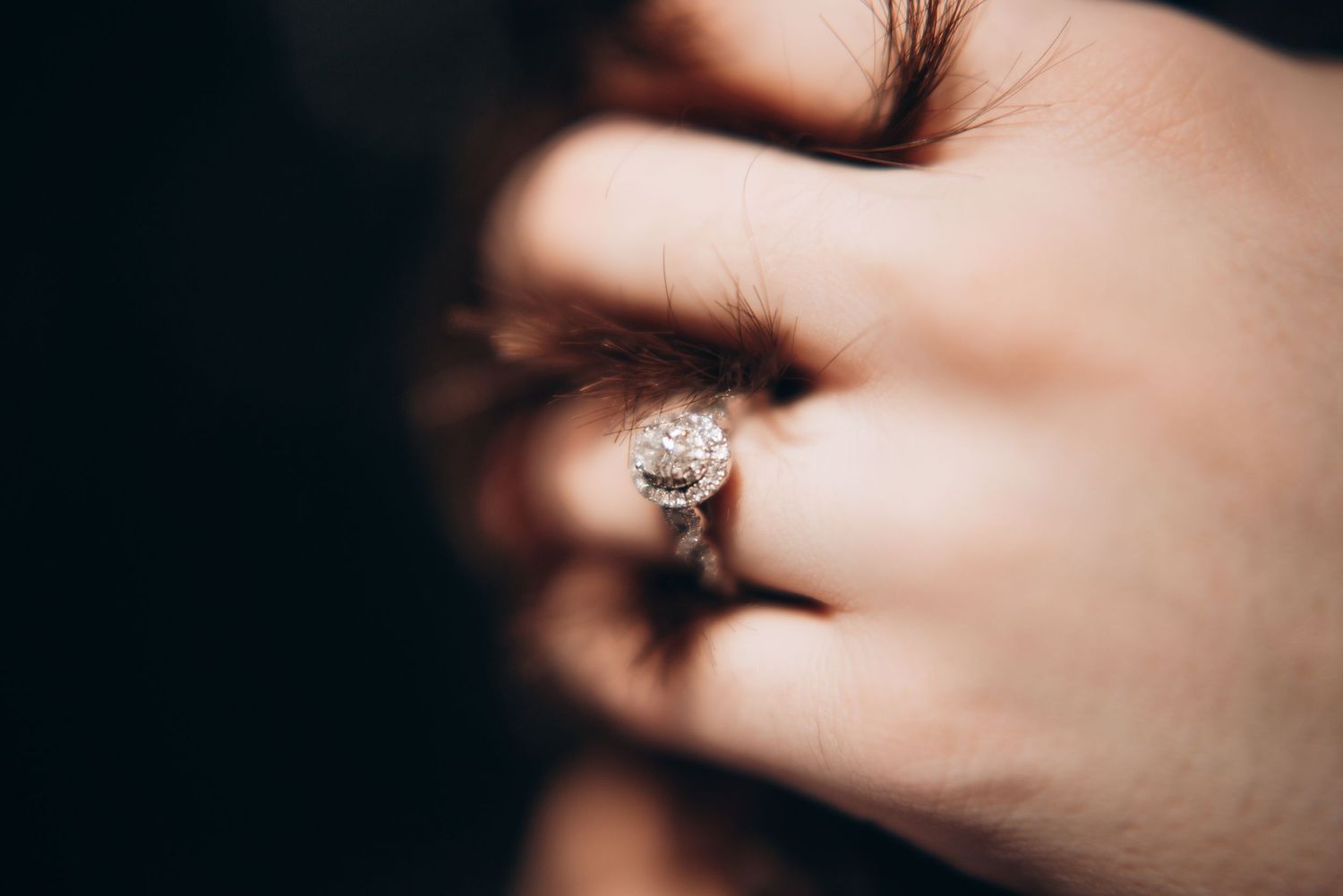 Close-up shot of hands with an engagement ring sparkling in soft focus.