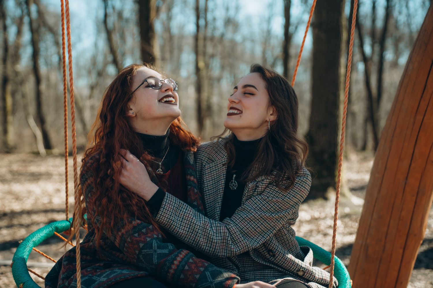 Couple laughing together on wooden bench during a winter day.