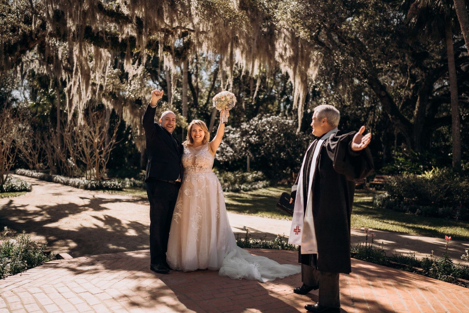 Wedding celebration in a garden setting with Spanish moss hanging from trees overhead.