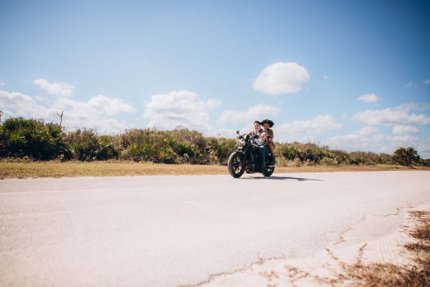 A motorcycle cruises along a scenic coastal road on a sunny day.