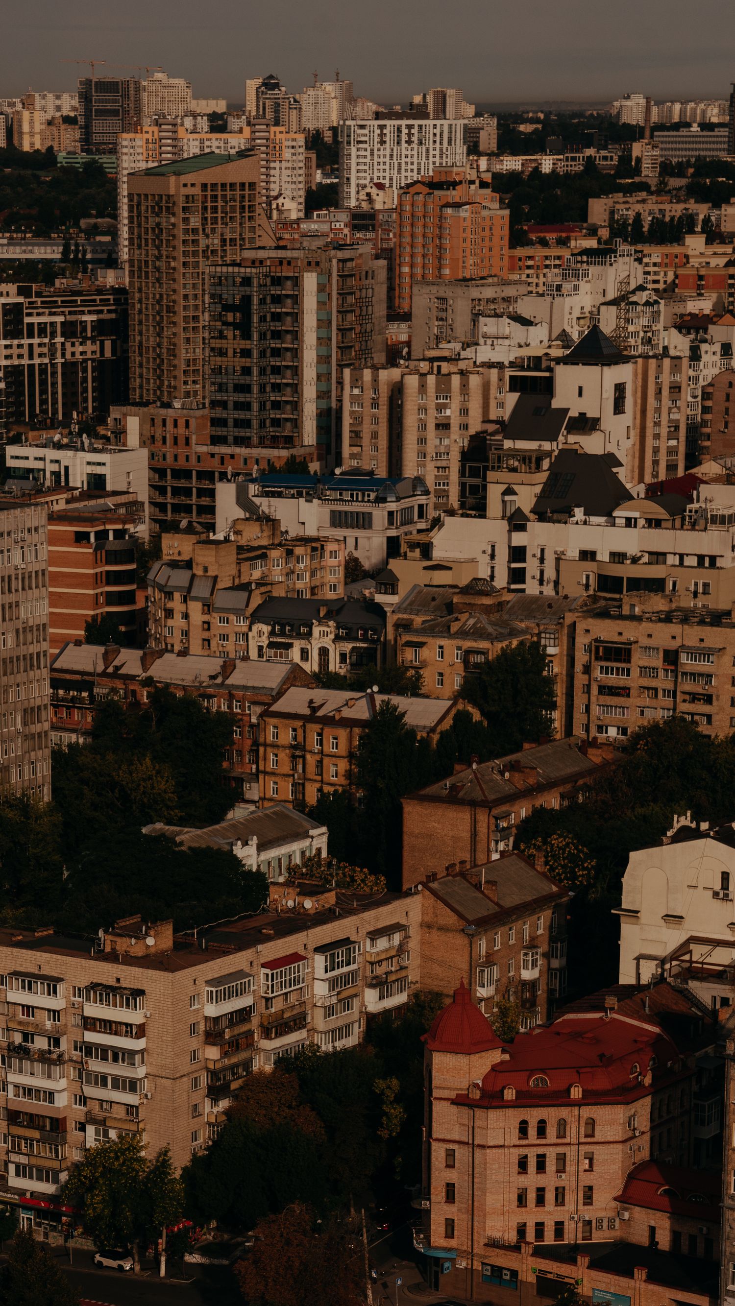 Aerial view of a dense urban cityscape with mix of modern and historic buildings bathed in warm golden light.