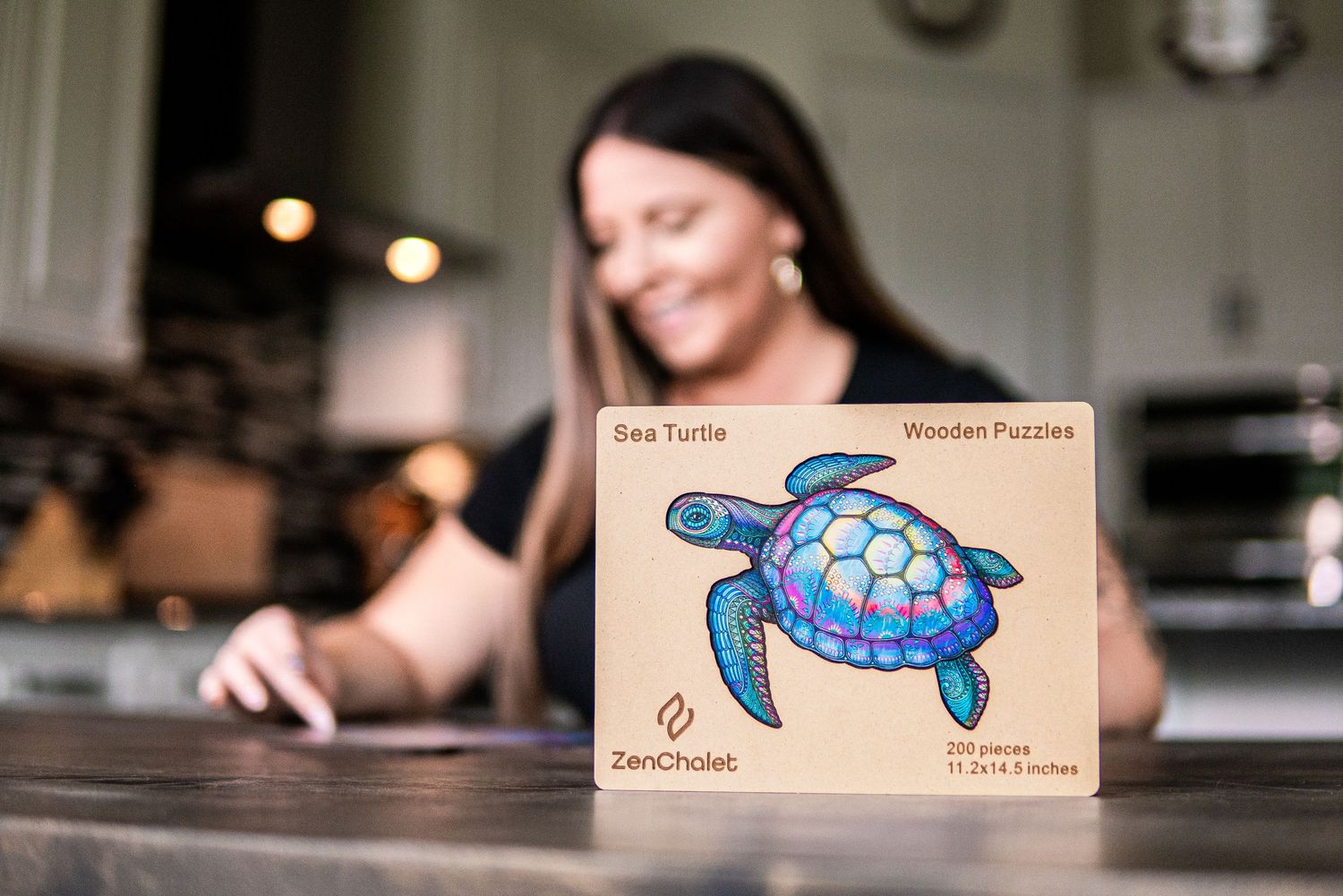 ZenChalet wooden Sea Turtle puzzle box displayed on a kitchen counter with woman in background.