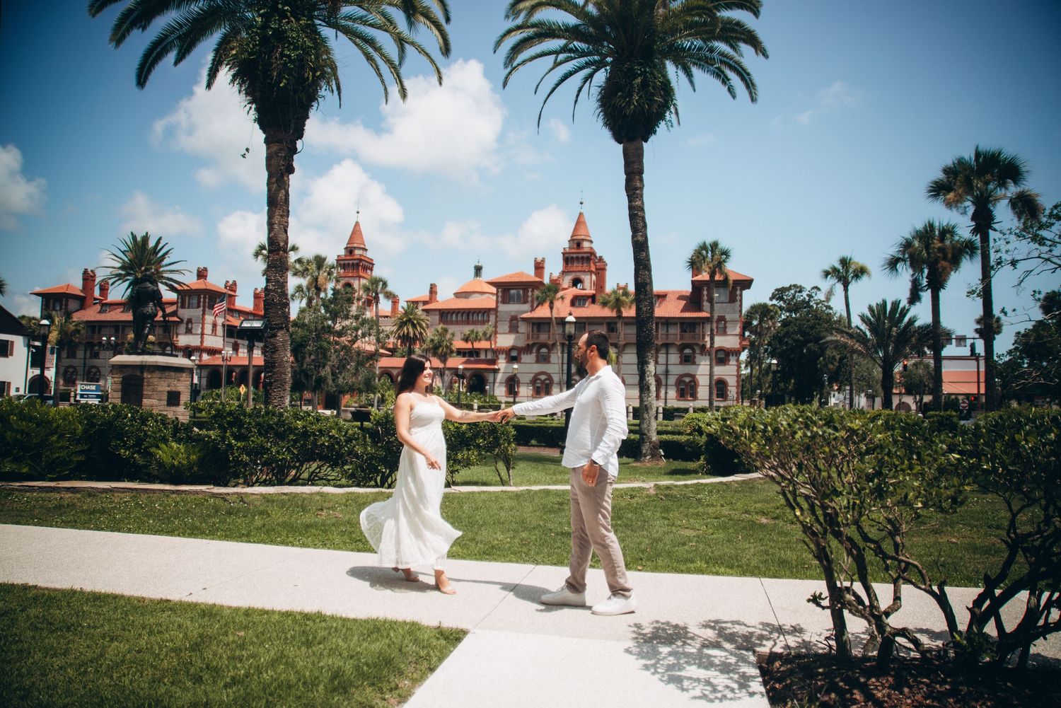 Couple dancing on a garden path with Flagler College's historic Spanish Renaissance building and palm trees in St. Augustine, FL.