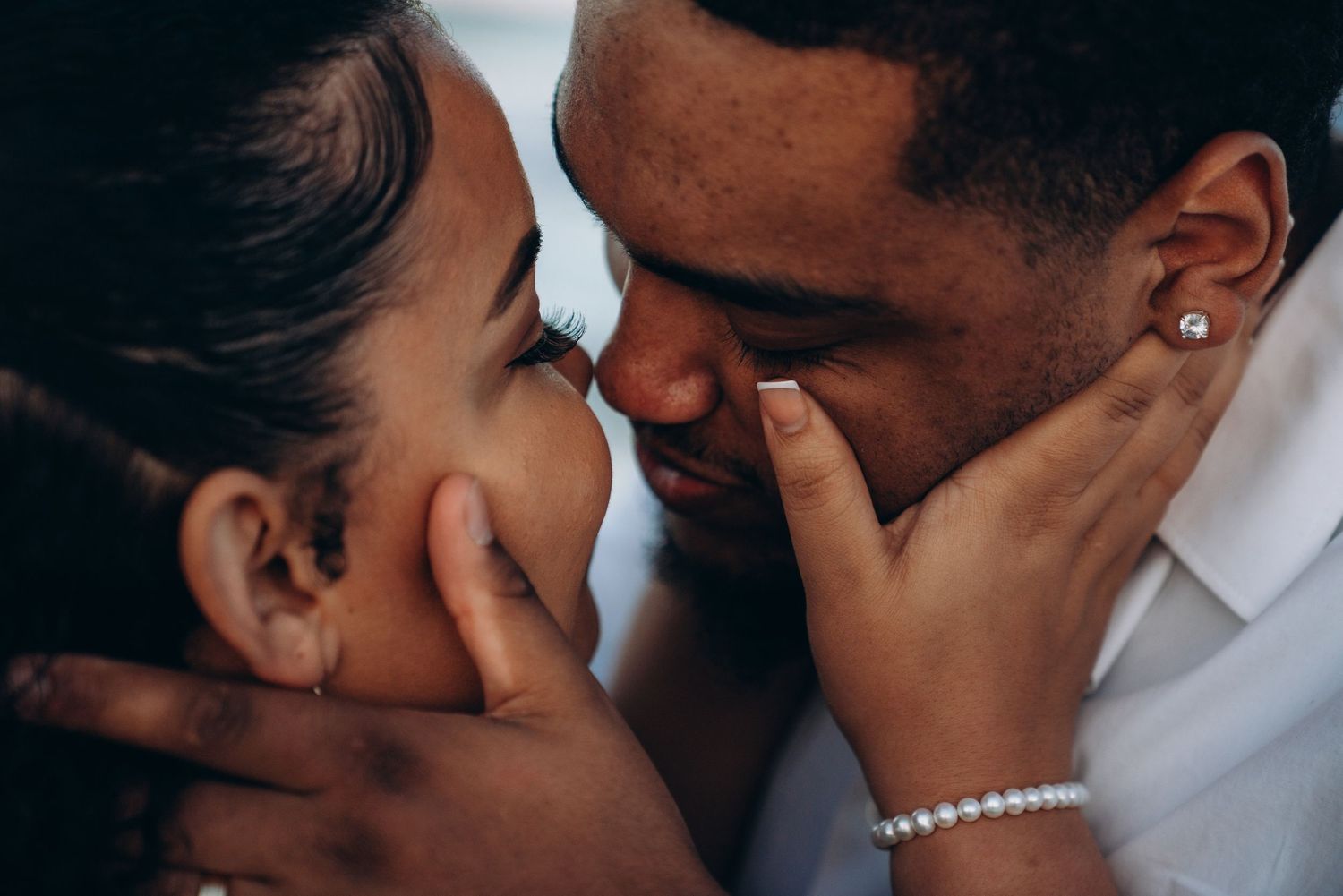 A romantic couple sharing an intimate moment, gently holding each other's faces close together.