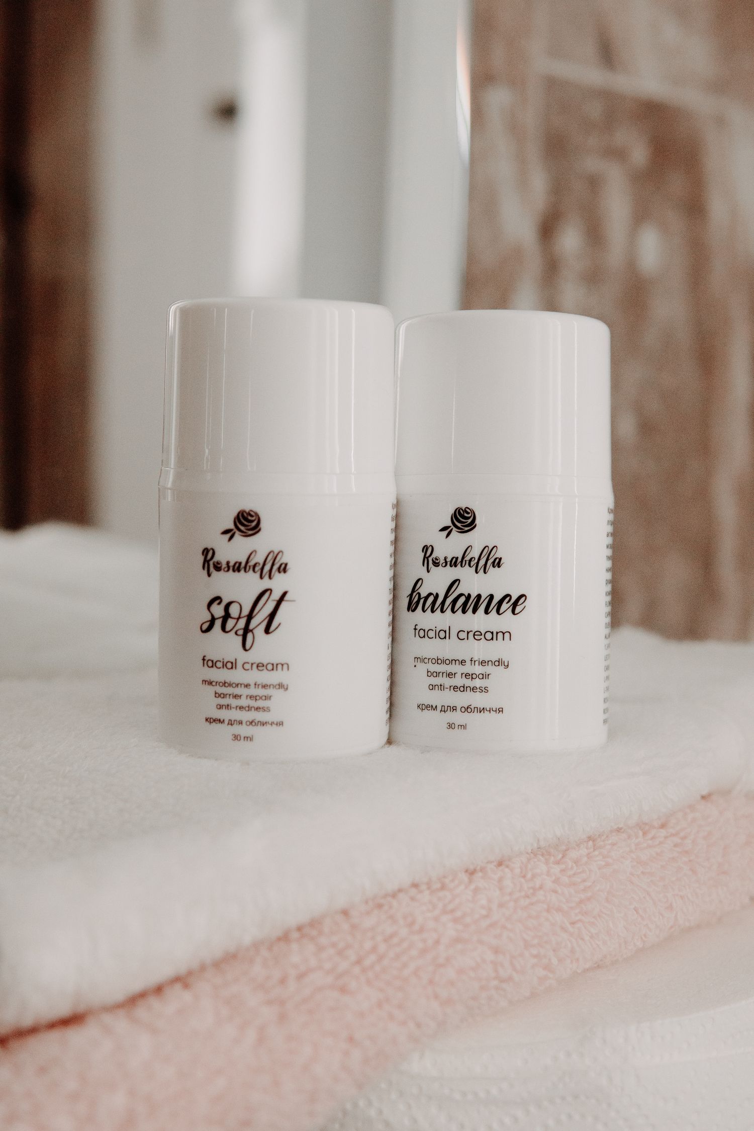 Rosabella Soft and Balance facial creams in white pump bottles on folded towels.