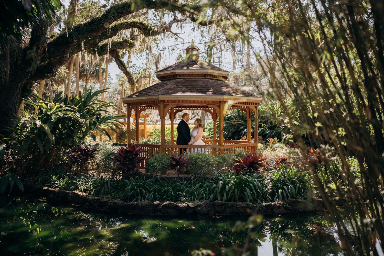 Elegant garden wedding venue with Spanish moss draped trees and a decorative gazebo.