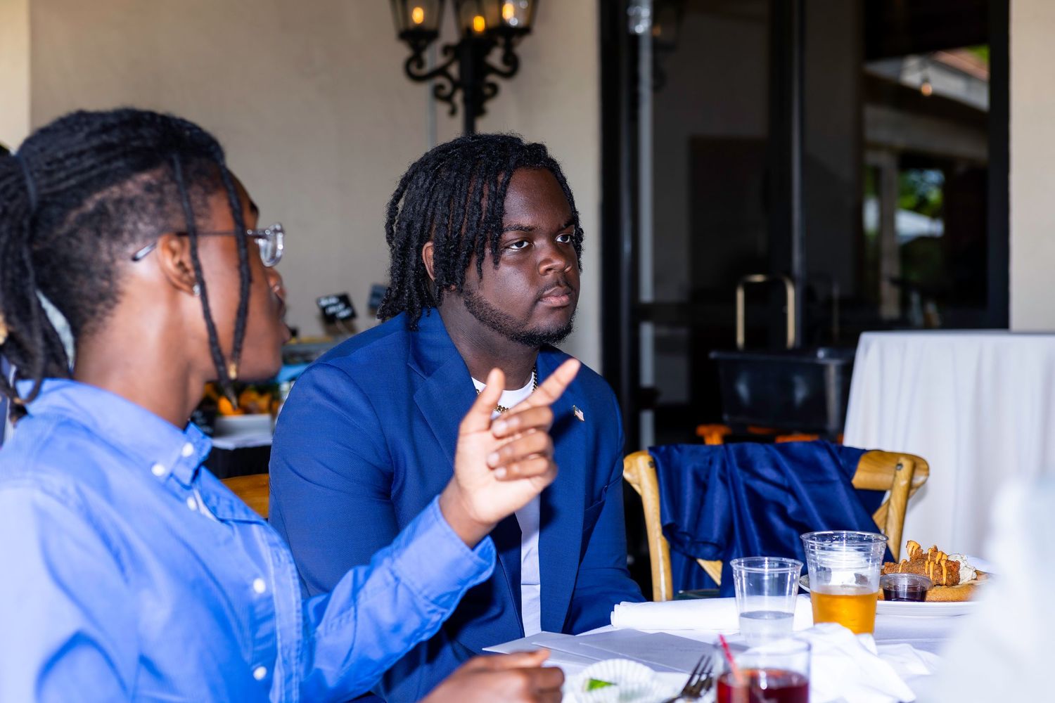 Group of attendees in blue attire engaged in conversation at a social gathering.
