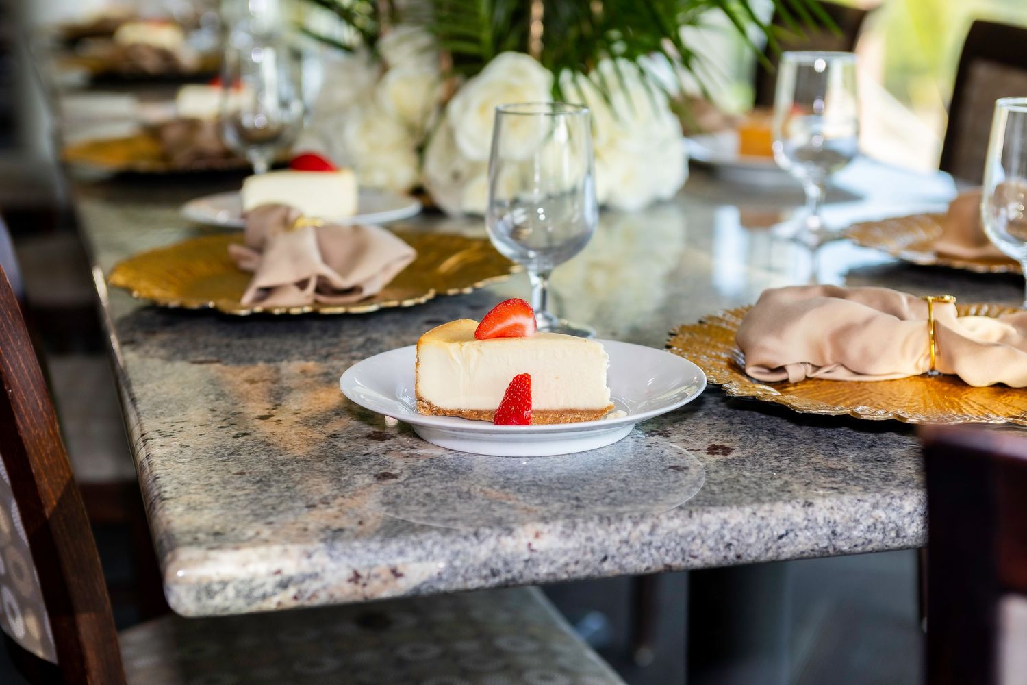 Elegant place setting with white dessert plate and wine glass on marble table.