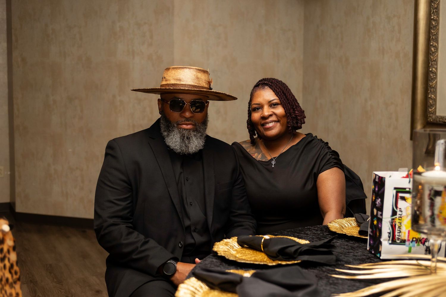 A couple at a formal event seated at an elegantly decorated black and gold table.
