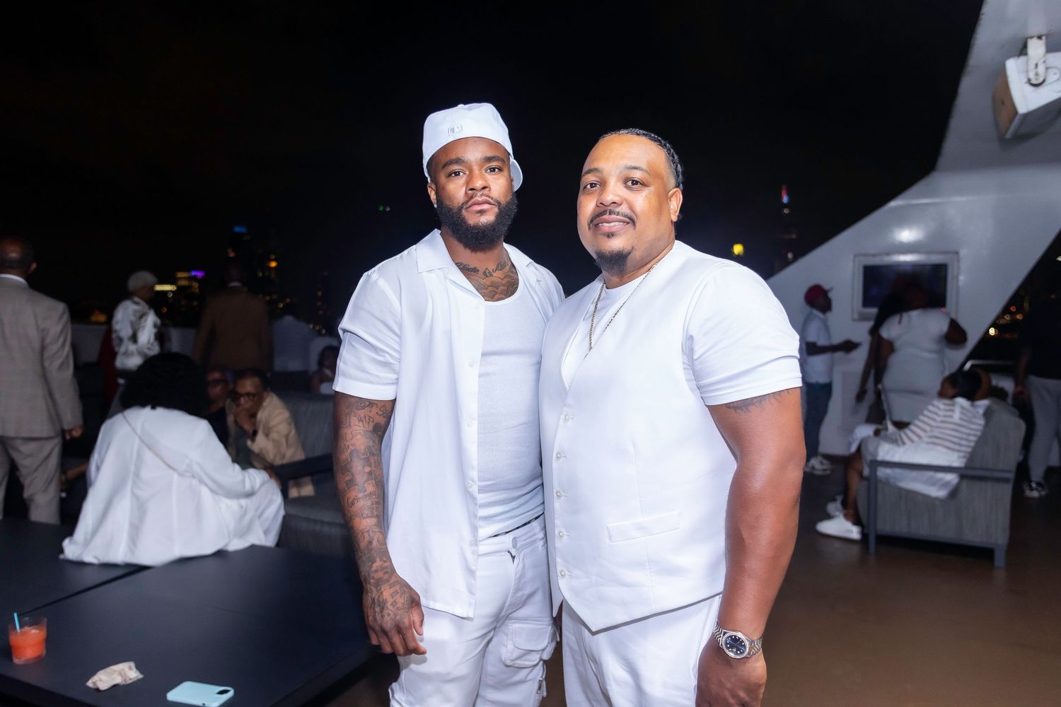 Two guests in all-white outfits pose together at a formal evening event.