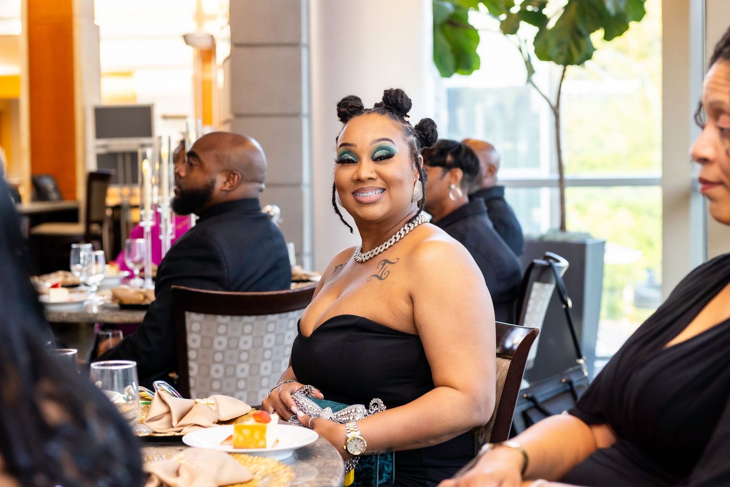 A festive social gathering with guests enjoying a meal at tables decorated with bright orange accents in a restaurant setting.