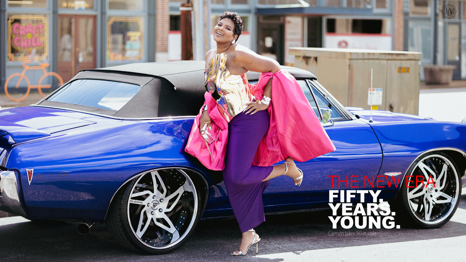 A stylish woman in purple pants and pink jacket poses beside a blue lowrider car with chrome rims, text reads Fifty Years Young.