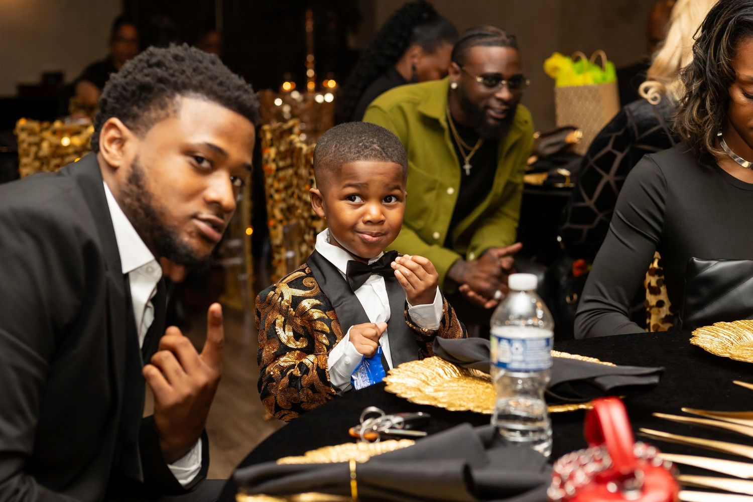 Guests socialize during an elegant evening gathering with sparkling gold decorative elements.