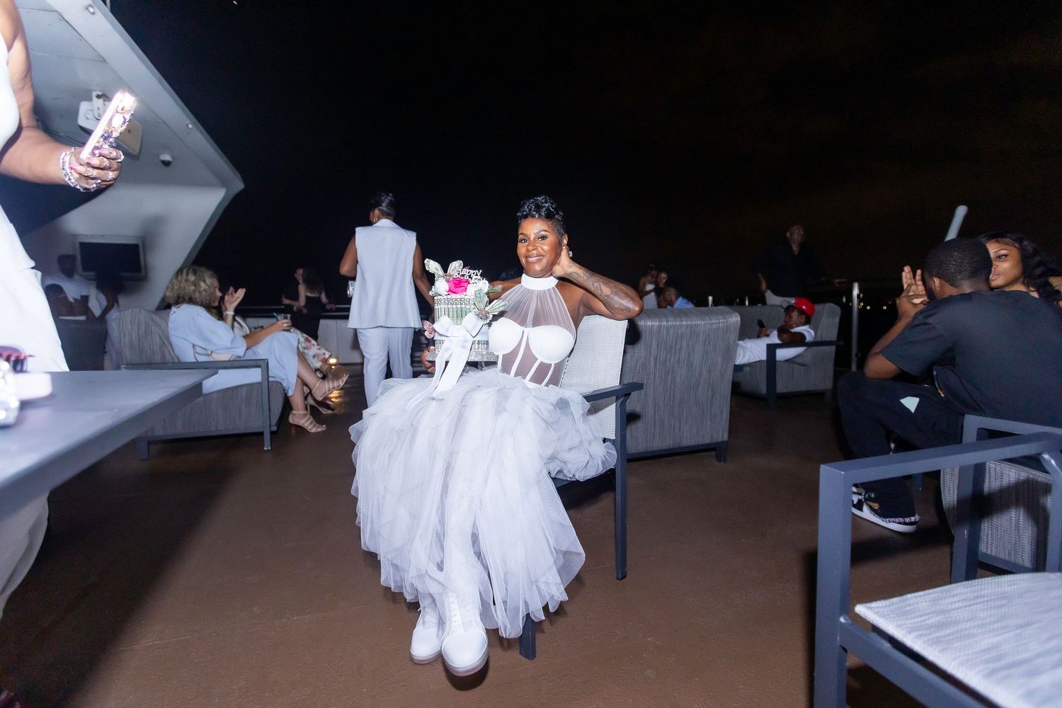 A person in a white tulle dress dancing at an evening celebration with outdoor seating.
