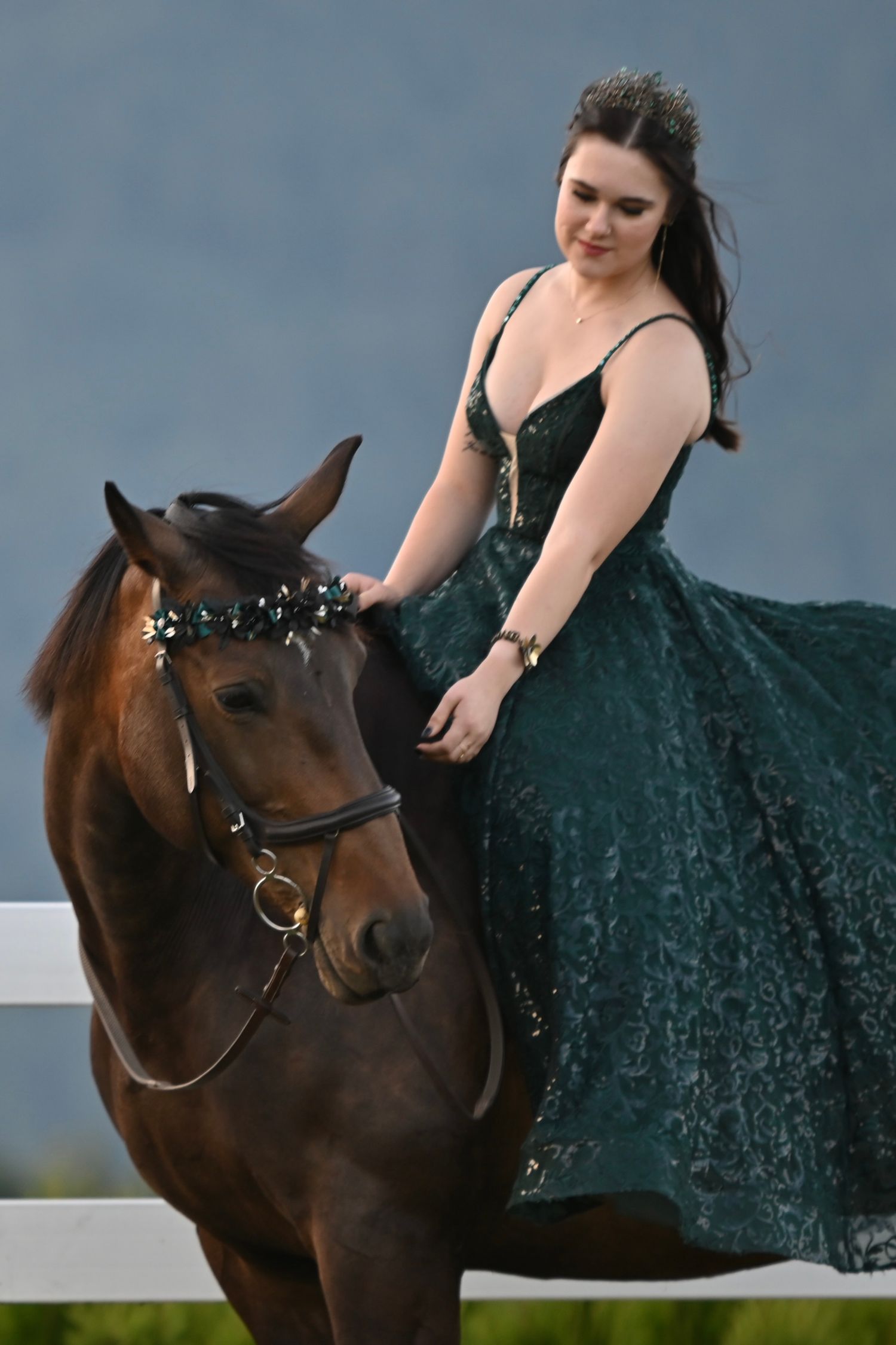 Female in green grad dress, sitting on horse and looking down
