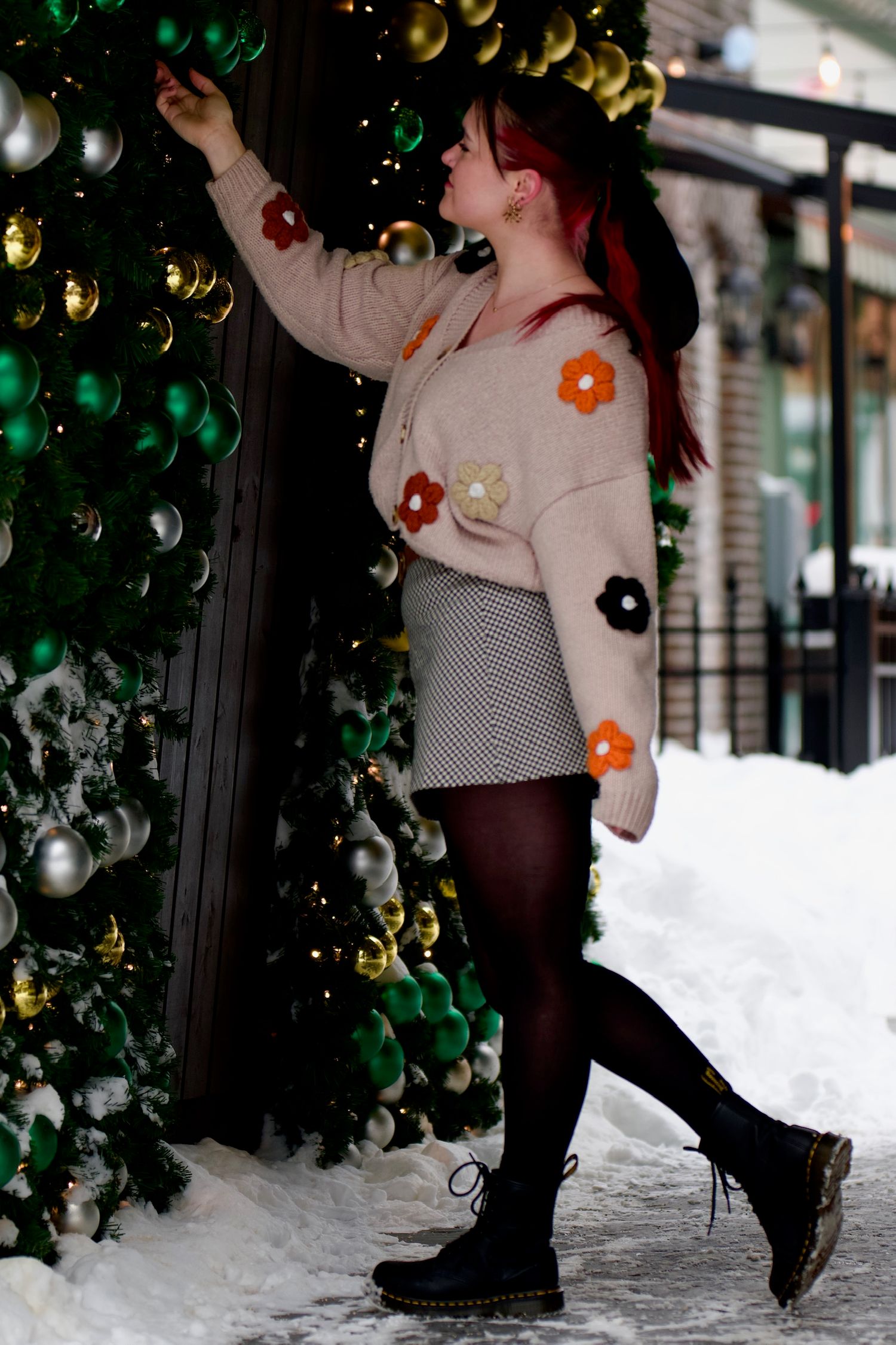 Female  reaching for Christmas bauble on large outdoor Christmas tree, Chilliwack