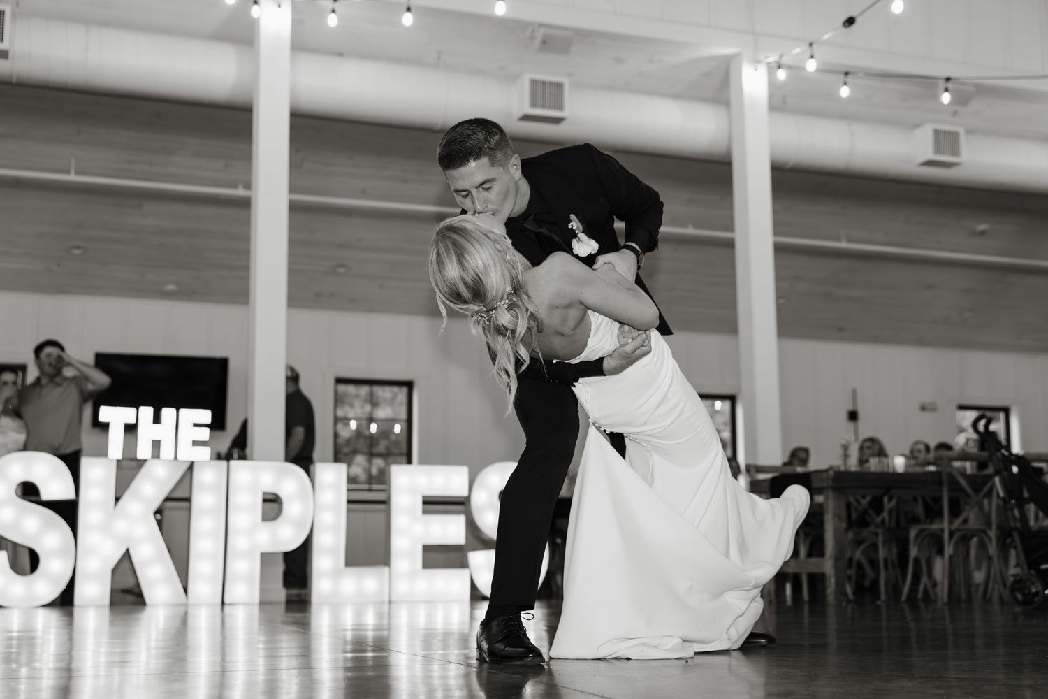 Black and white image of a dancer in mid-leap performing a grand jete across a bright dance studio space.