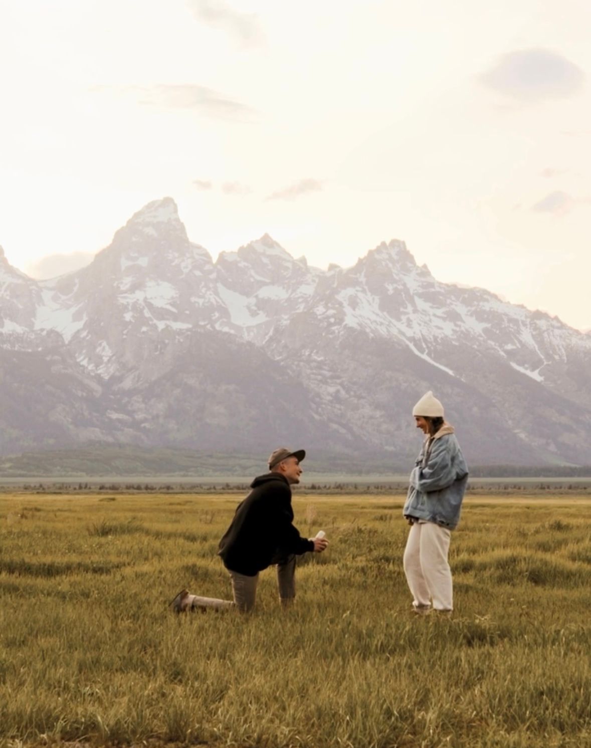 A proposal moment against a backdrop of majestic mountain peaks during sunset.