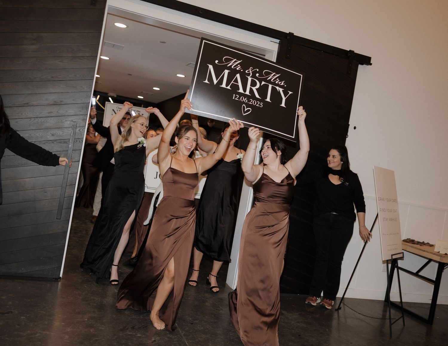 A group of people celebrating at an event venue with a 'Marty' sign visible in the background.