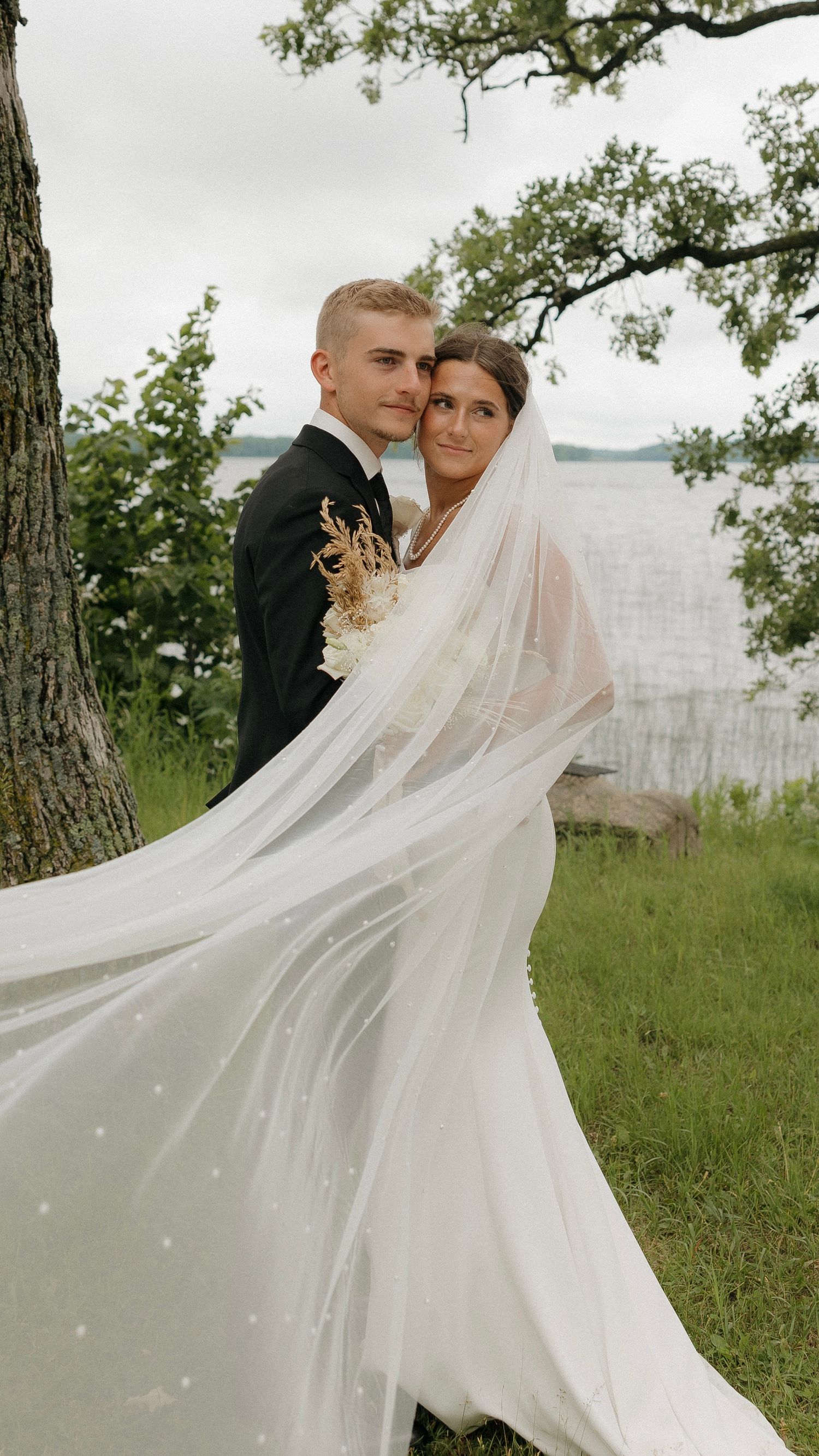 A flowing white wedding veil creates dramatic movement in an outdoor portrait session.