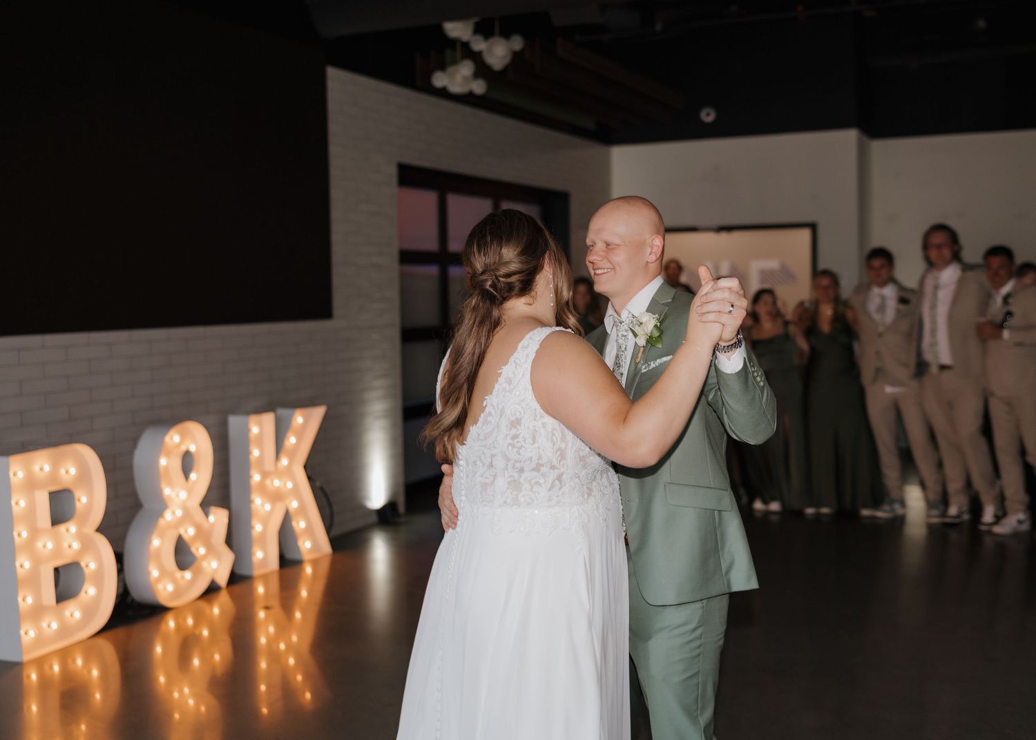 Illuminated marquee letters spell B&K at a dimly lit wedding reception venue.
