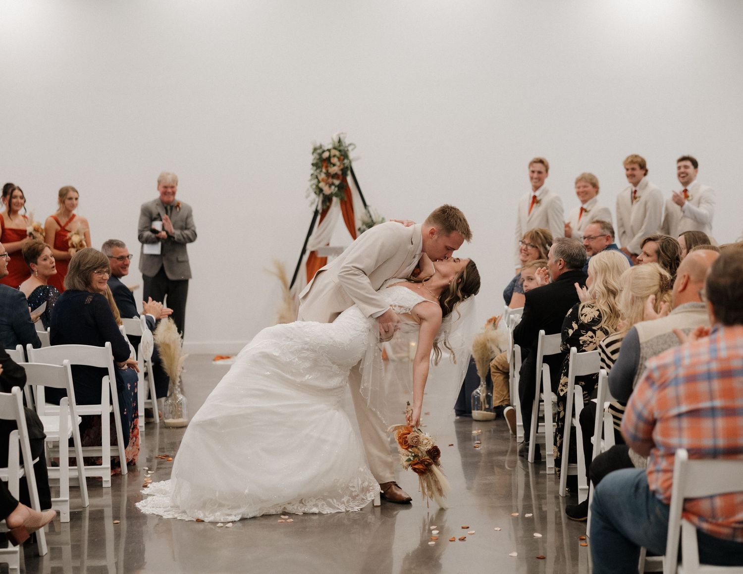 A modern white wedding ceremony space with guests seated in white chairs and minimalist decor.