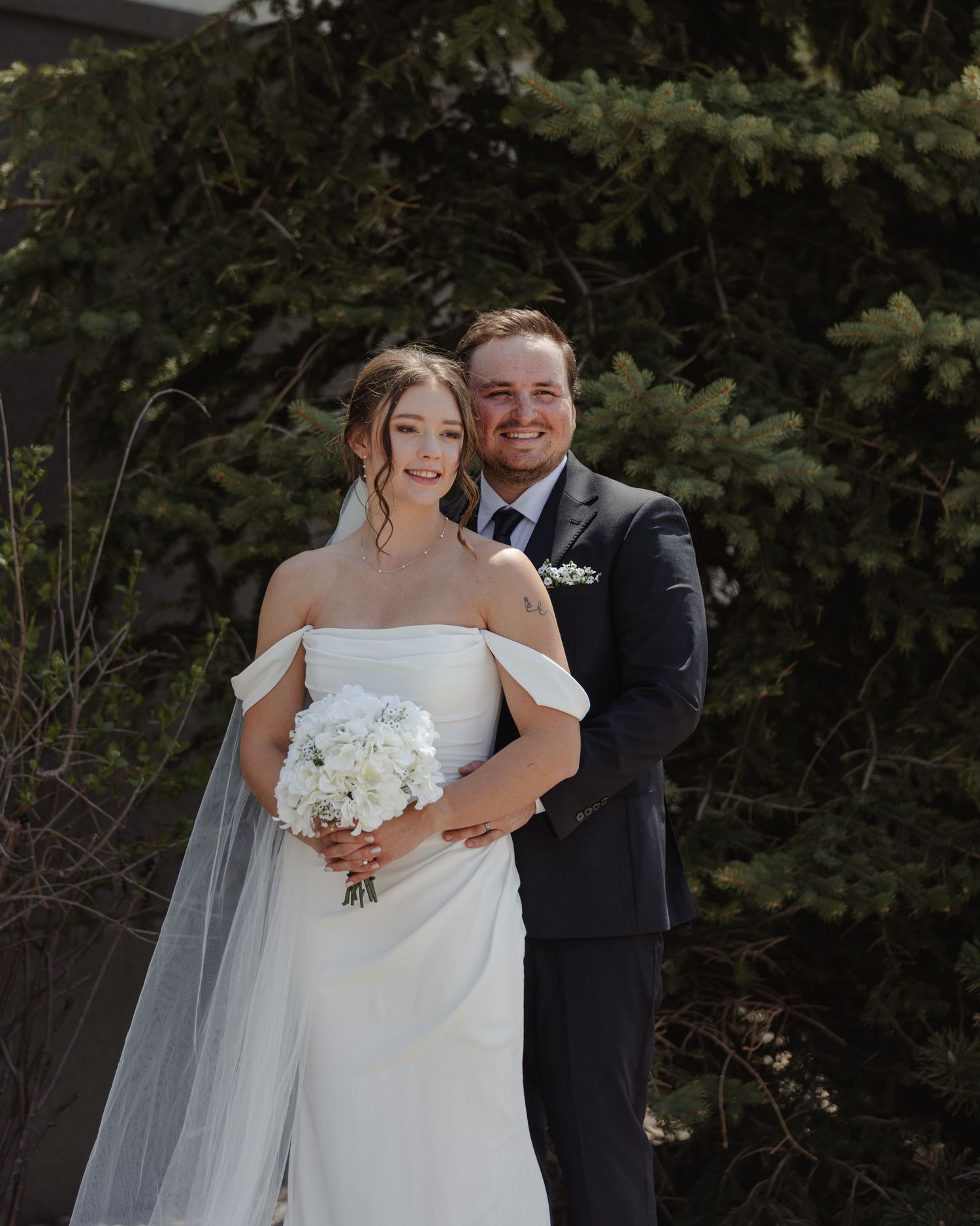 Newlywed couple shares intimate moments during outdoor wedding photoshoot in a lush garden setting.