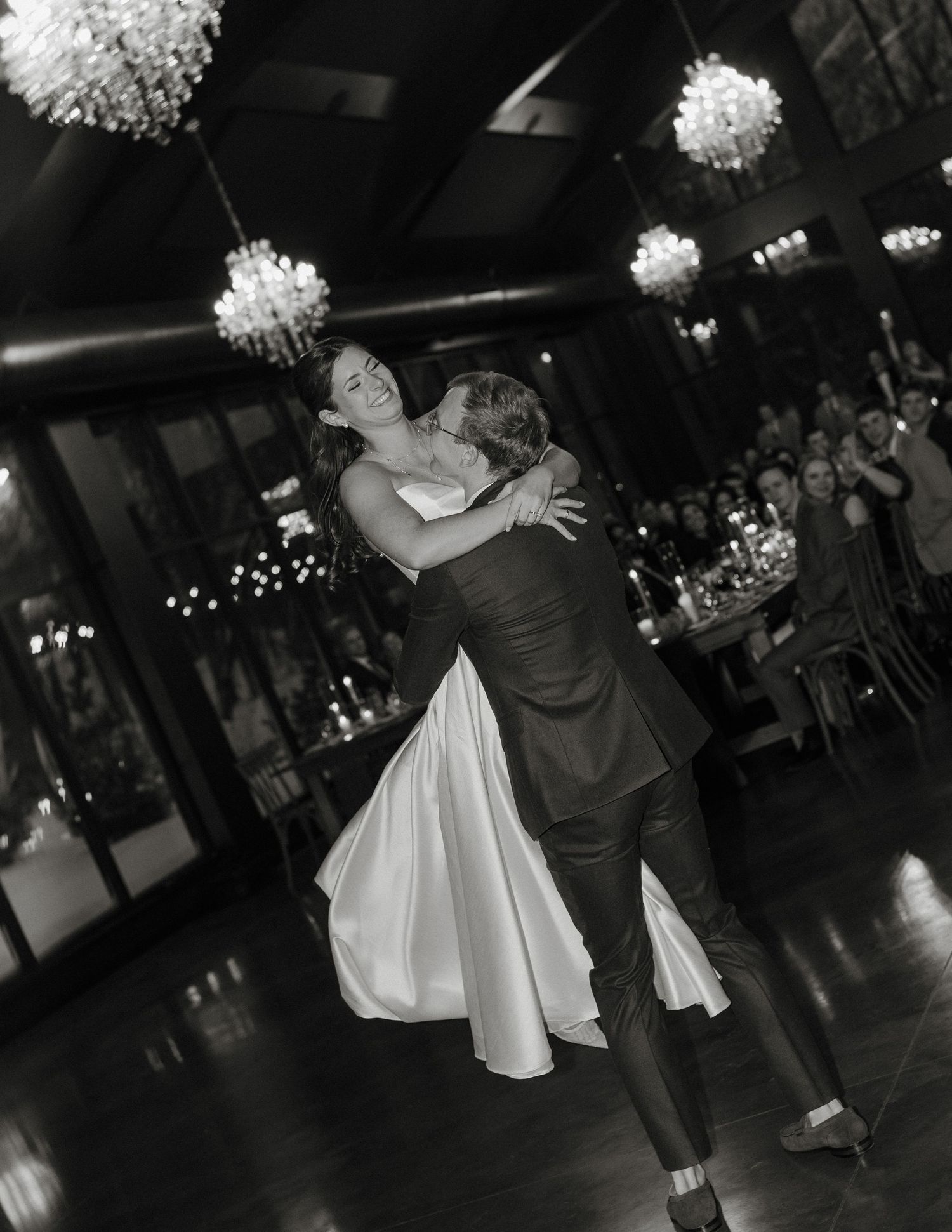 A couple shares a romantic dance at their wedding reception under elegant white floral decorations.