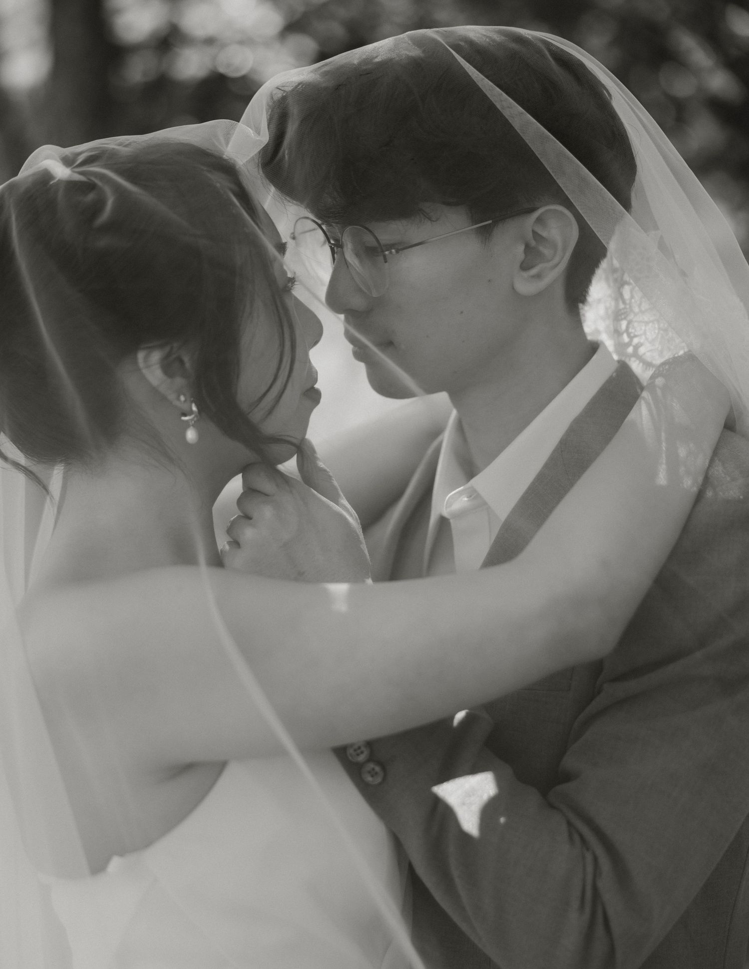 A romantic black and white wedding photograph showing a tender moment between a bride and groom.
