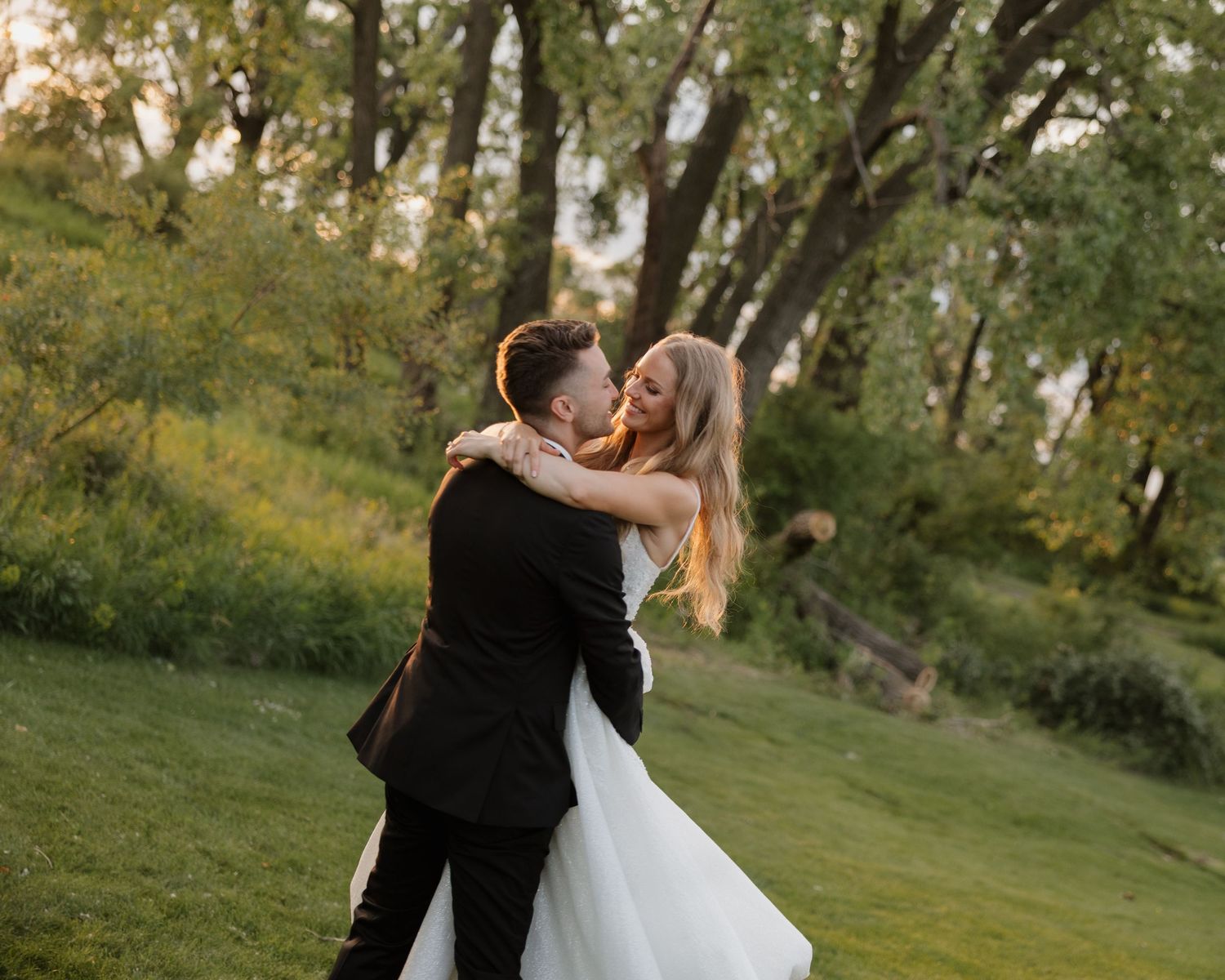A couple shares romantic moments in a lush outdoor setting during their wedding photoshoot.