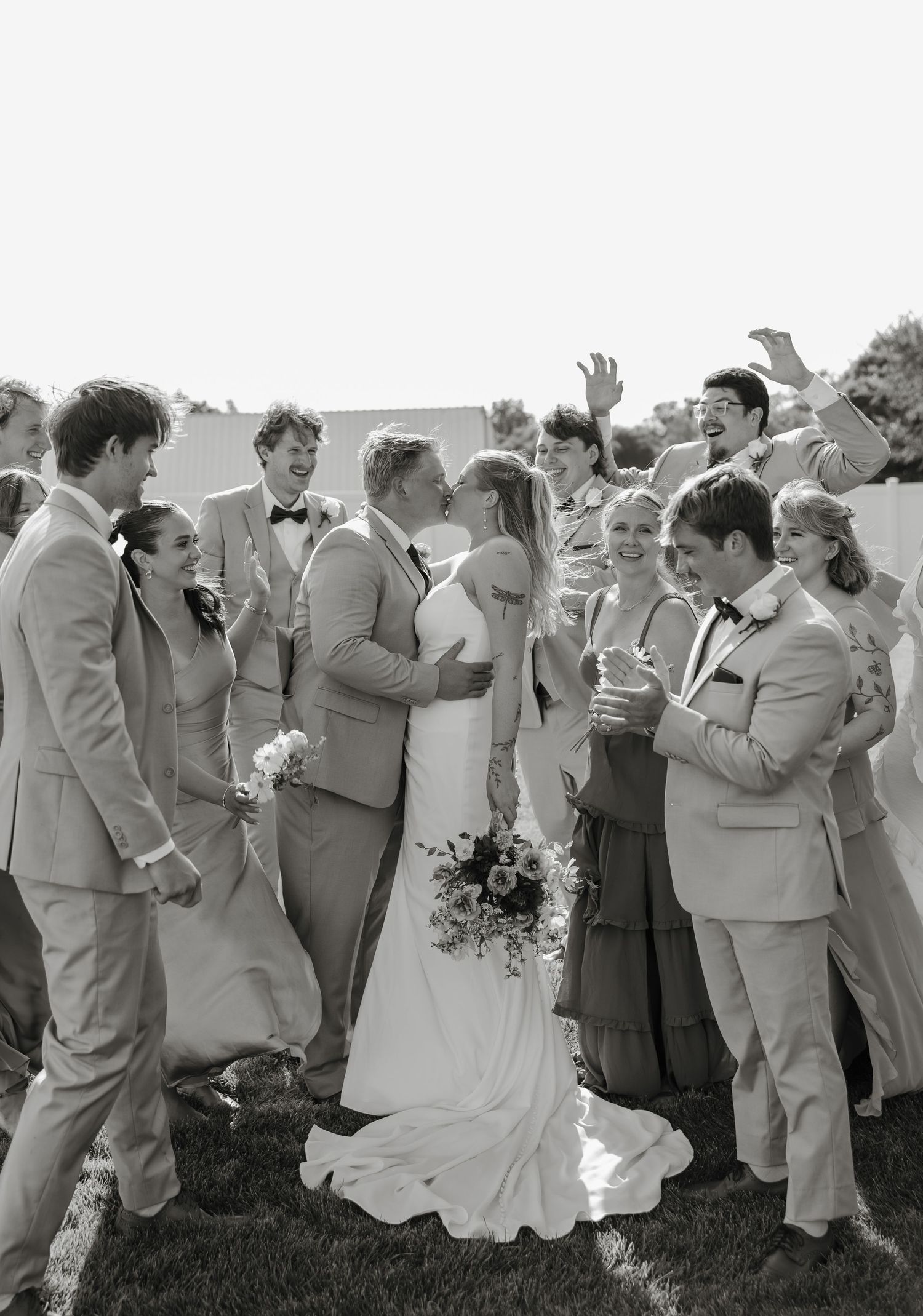 Black and white wedding photo showing a celebration with wedding party members gathered on a lawn.