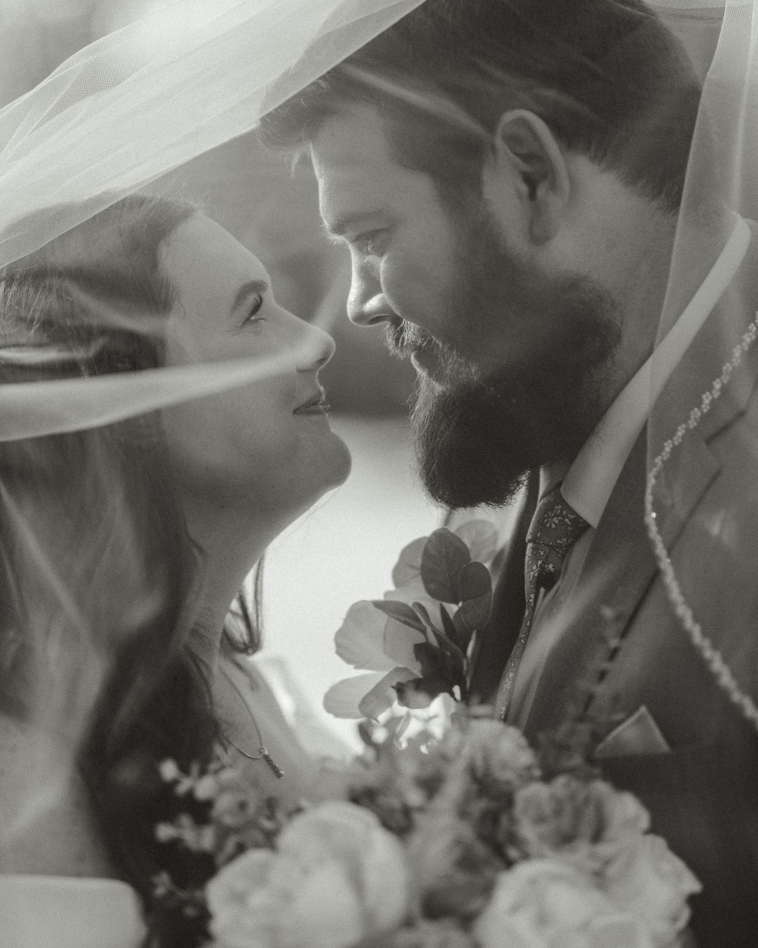 A black and white wedding photo montage showing intimate moments between newlyweds with flowing veil and floral bouquet details.
