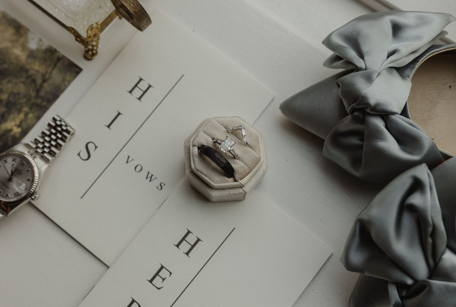 Wedding stationery and rings styled with gray silk bow accessories.
