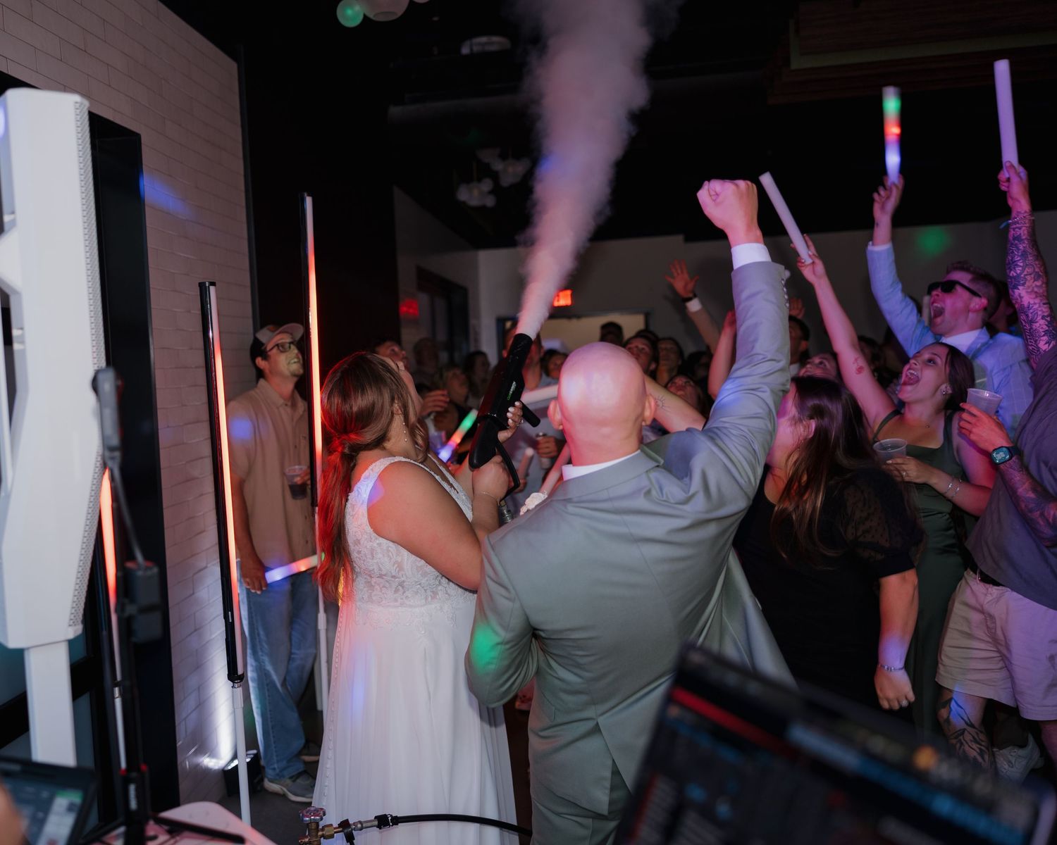 Silhouettes of people dancing at a dimly lit party with purple lighting in the background.