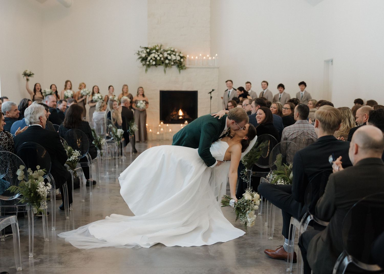 A series of wedding ceremony moments showing guests seated in a modern white venue with flowing drapery and floral decor.